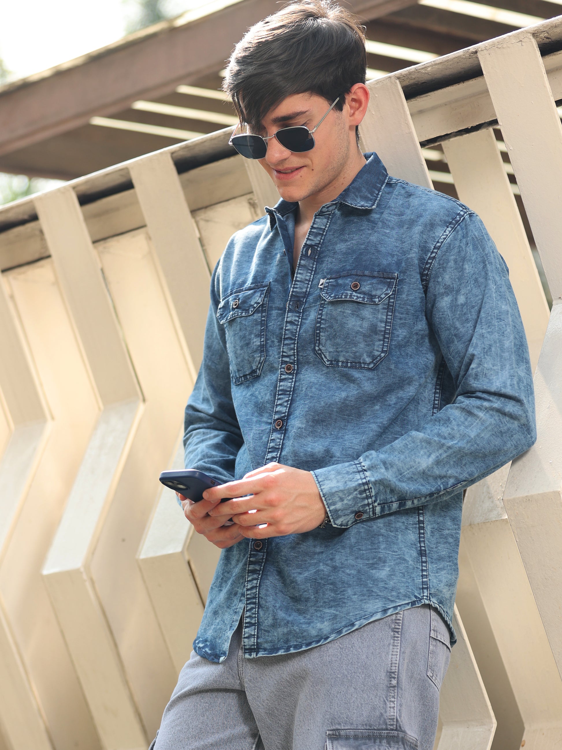 Modern men’s denim shirt with washed texture, full sleeves, and chest pockets, styled casually.