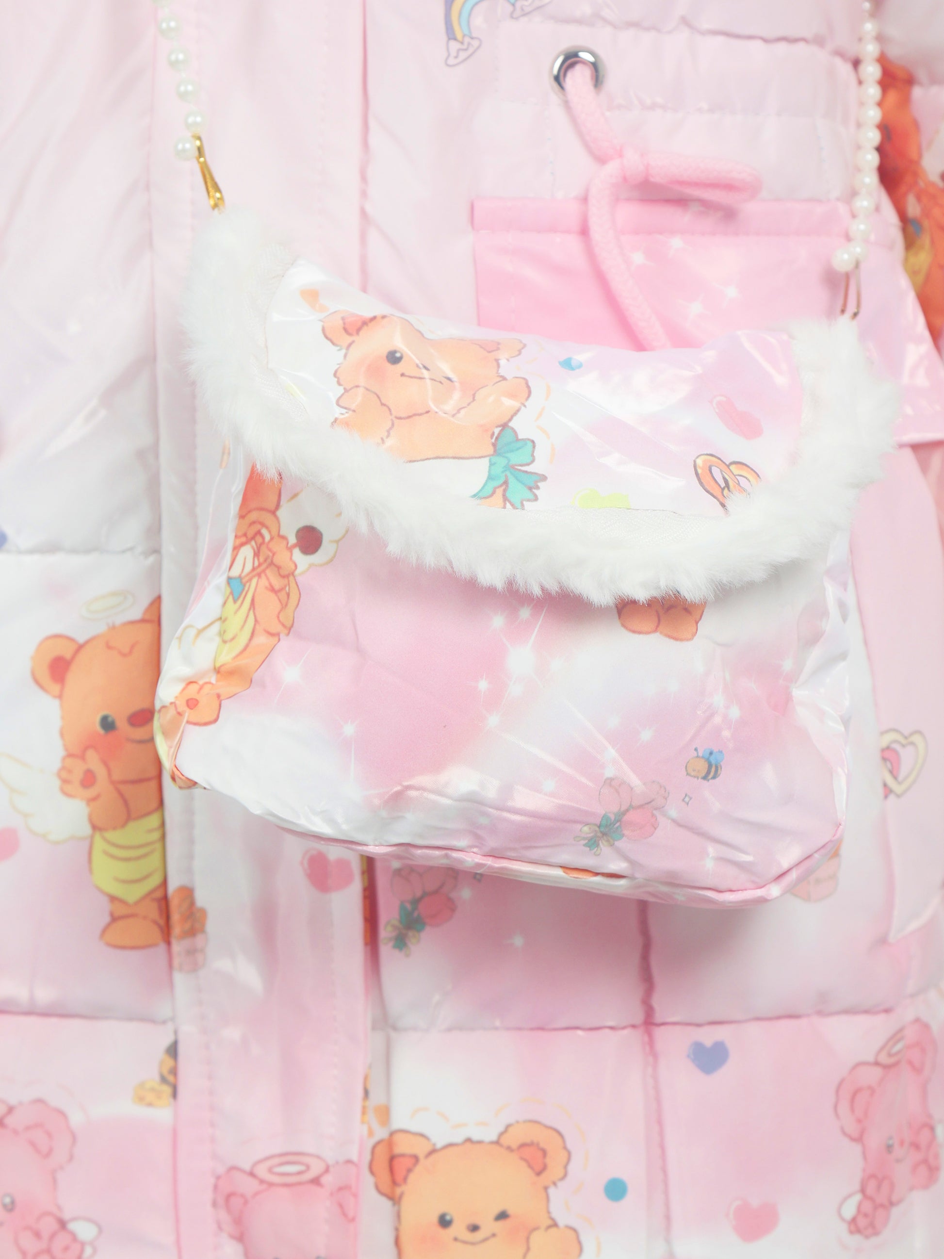 Close-up of a pink children’s winter jacket with teddy bear prints, featuring a matching small shoulder bag with white faux fur trim and pearl strap detail.