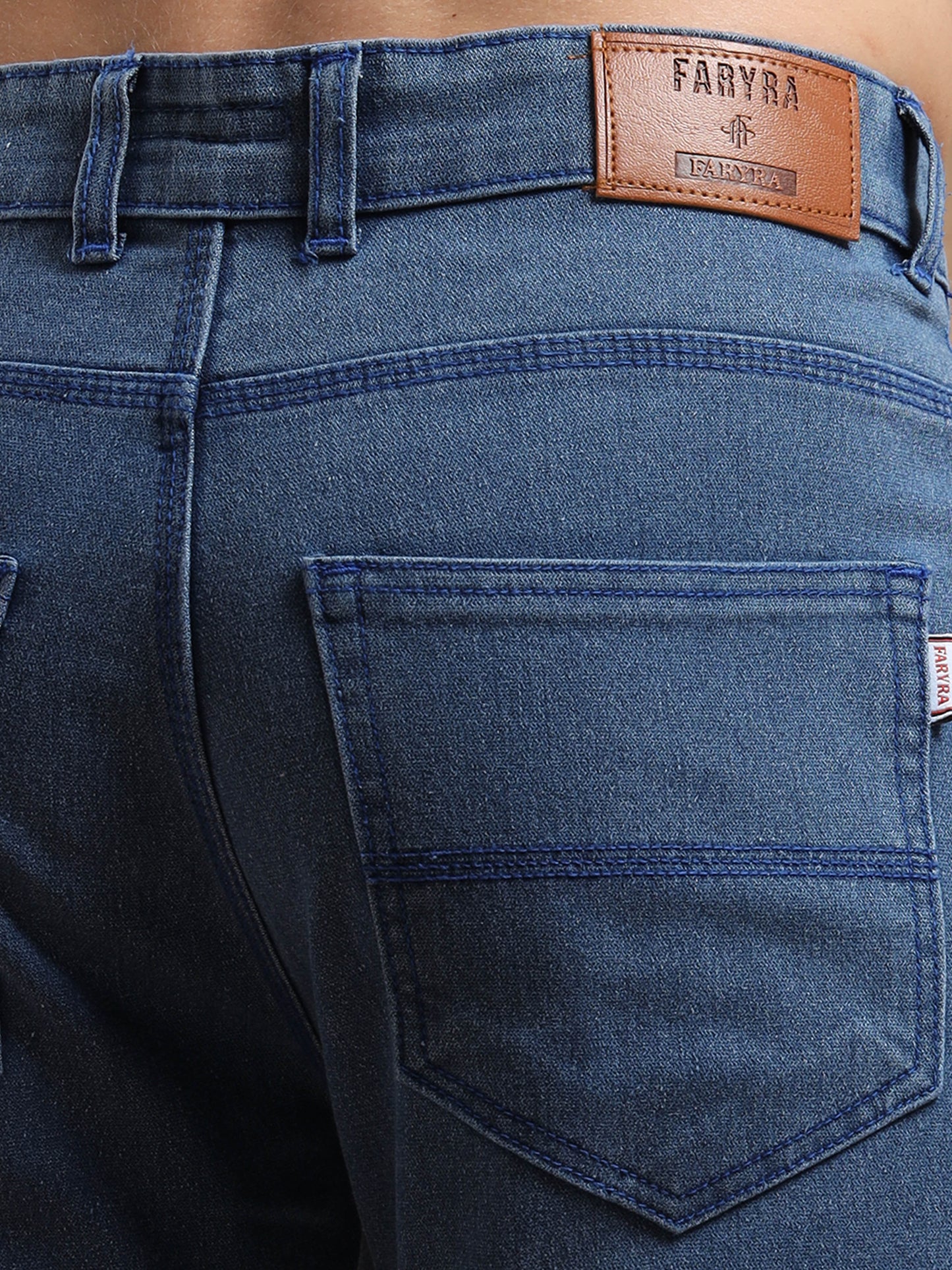 Close-up of back pocket and brown leather brand tag on men’s blue jeans