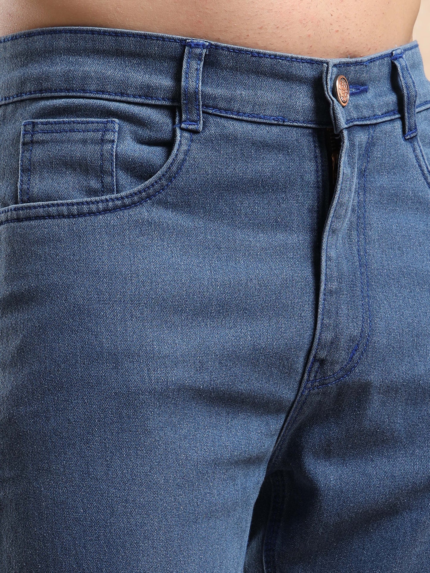 Close-up of front waist and pocket details on blue denim jeans