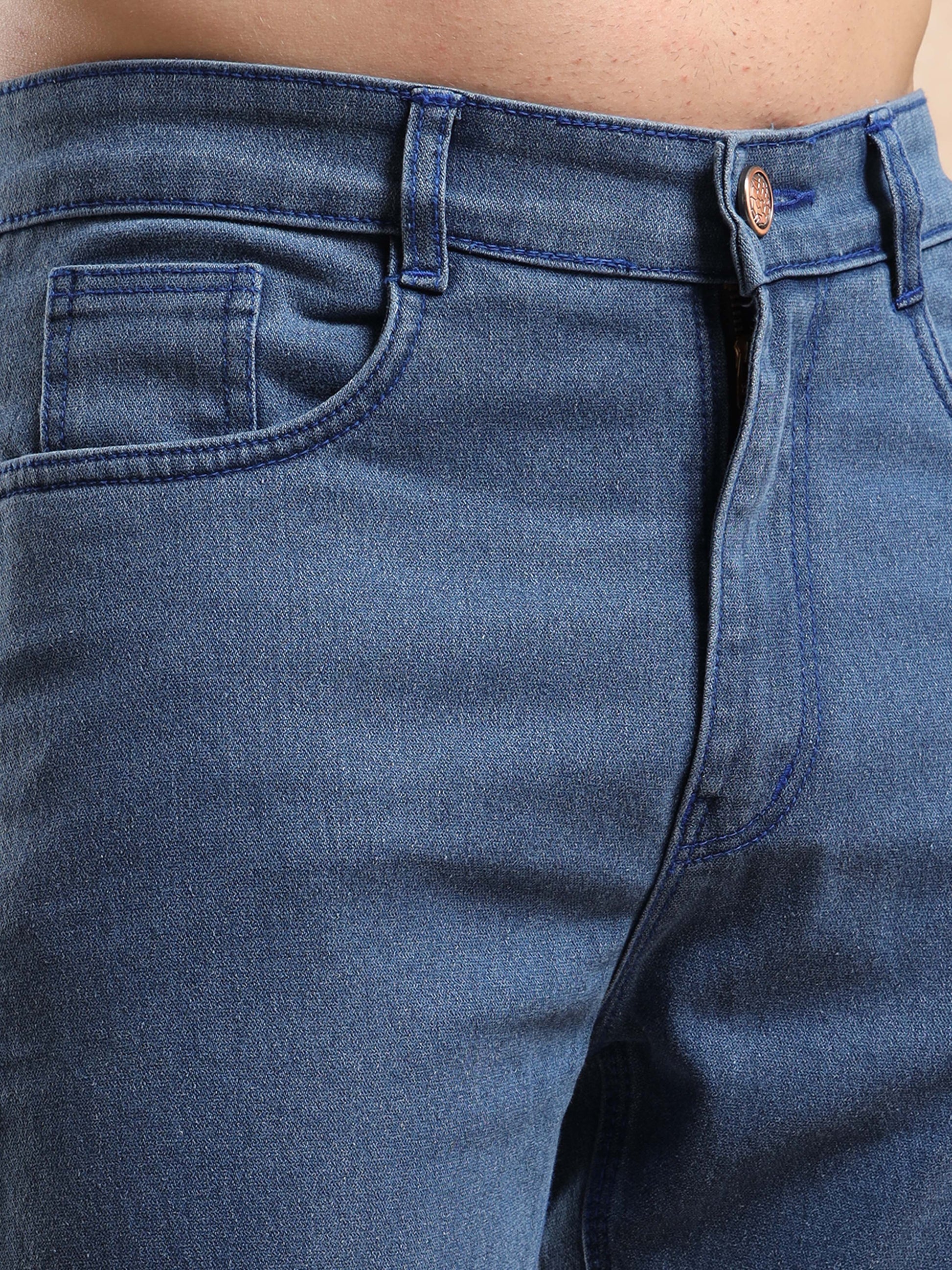 Close-up of front waist and pocket details on blue denim jeans