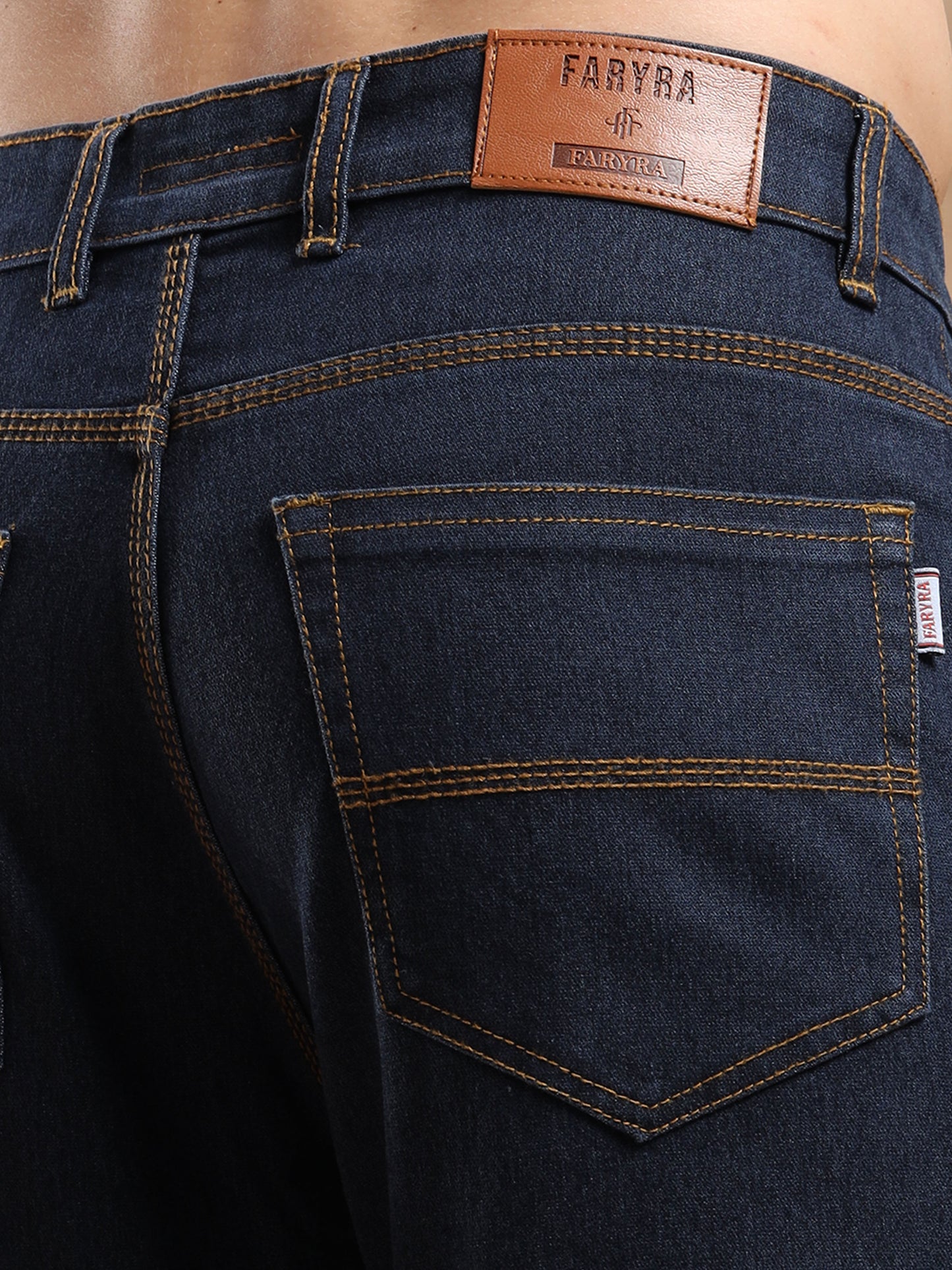 Detailed back pocket and leather brand patch of men’s denim jeans