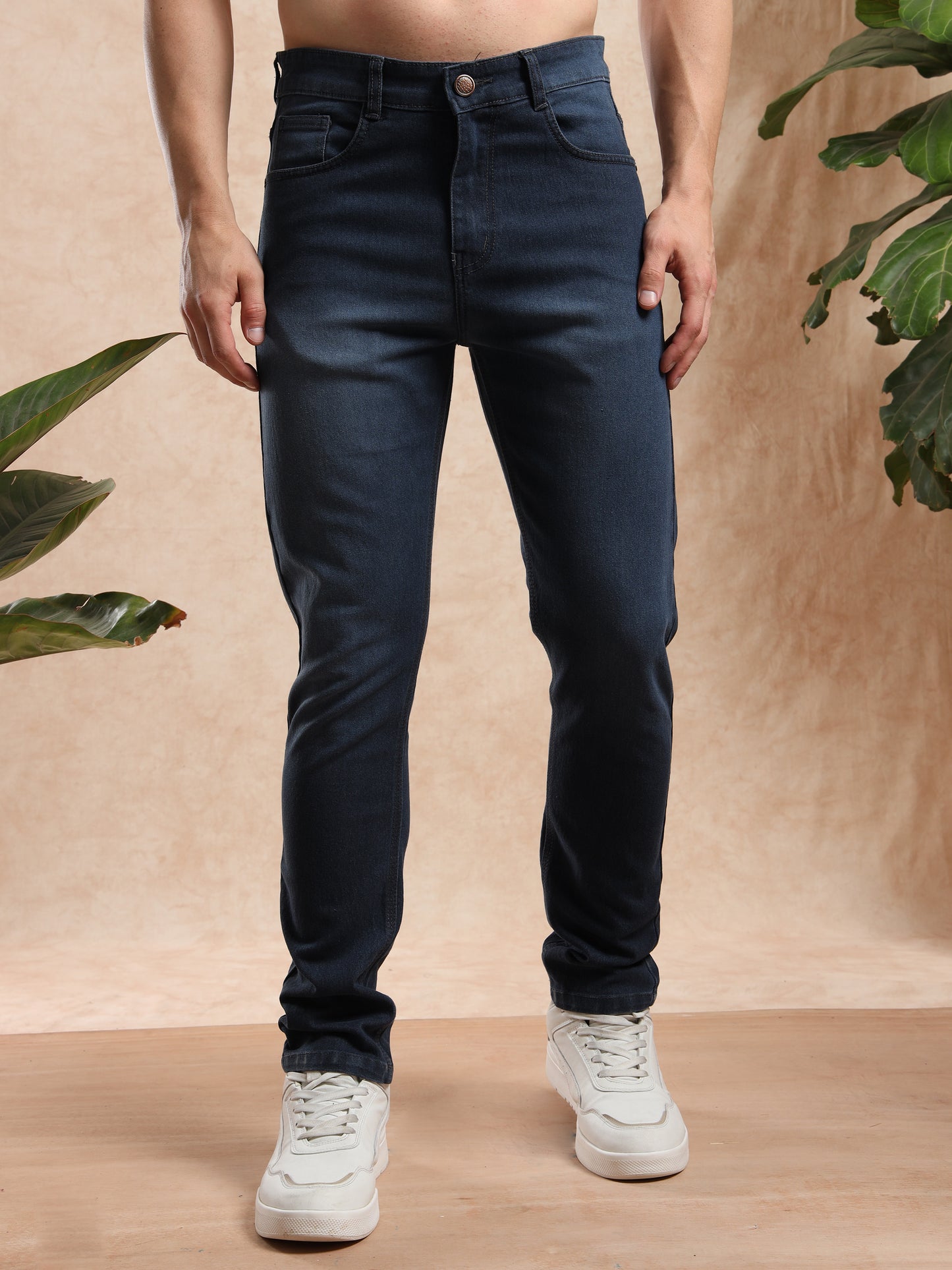 Men’s slim fit dark wash denim jeans paired with white sneakers, front view.