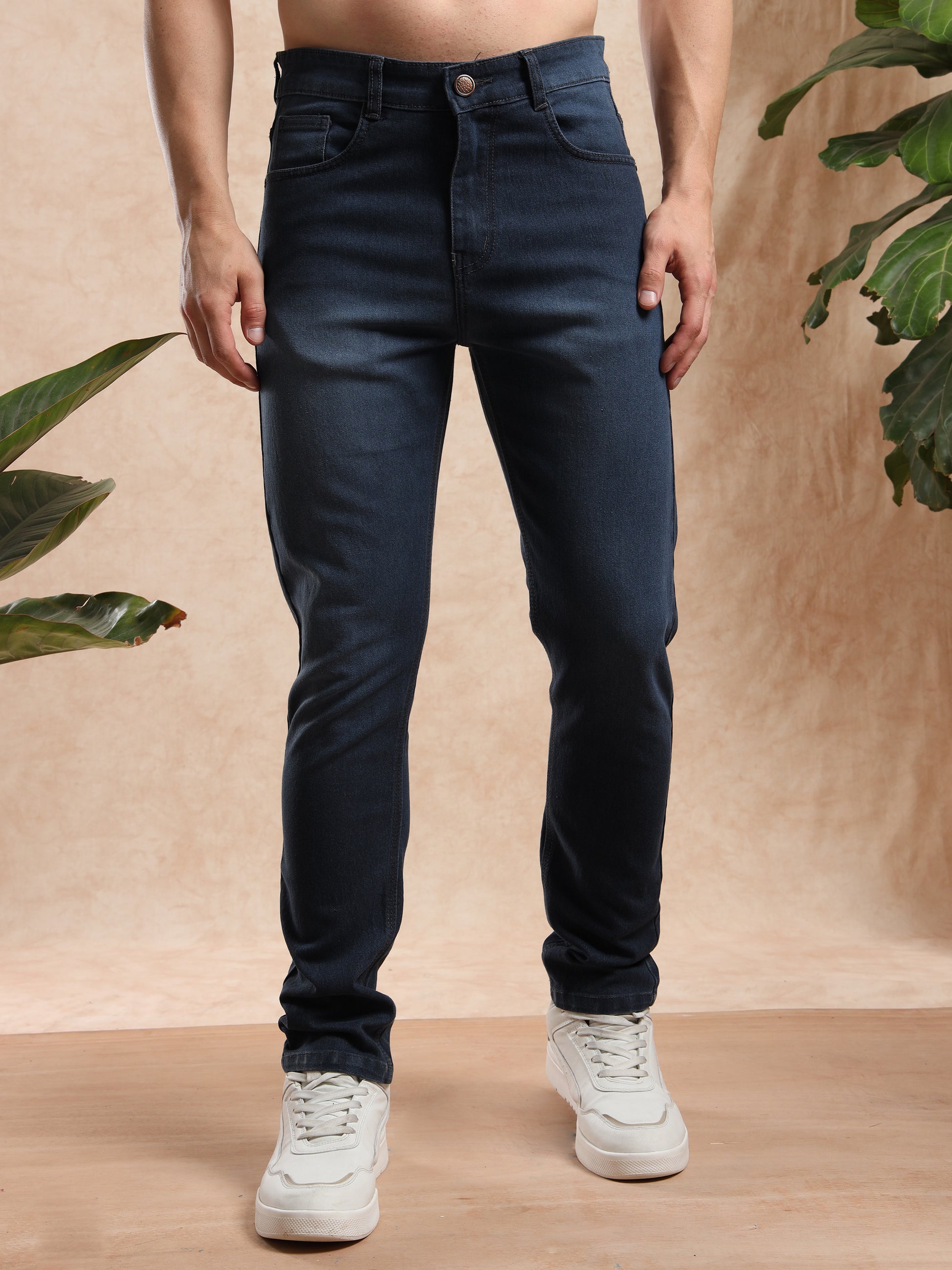 Men’s slim fit dark wash denim jeans paired with white sneakers, front view.