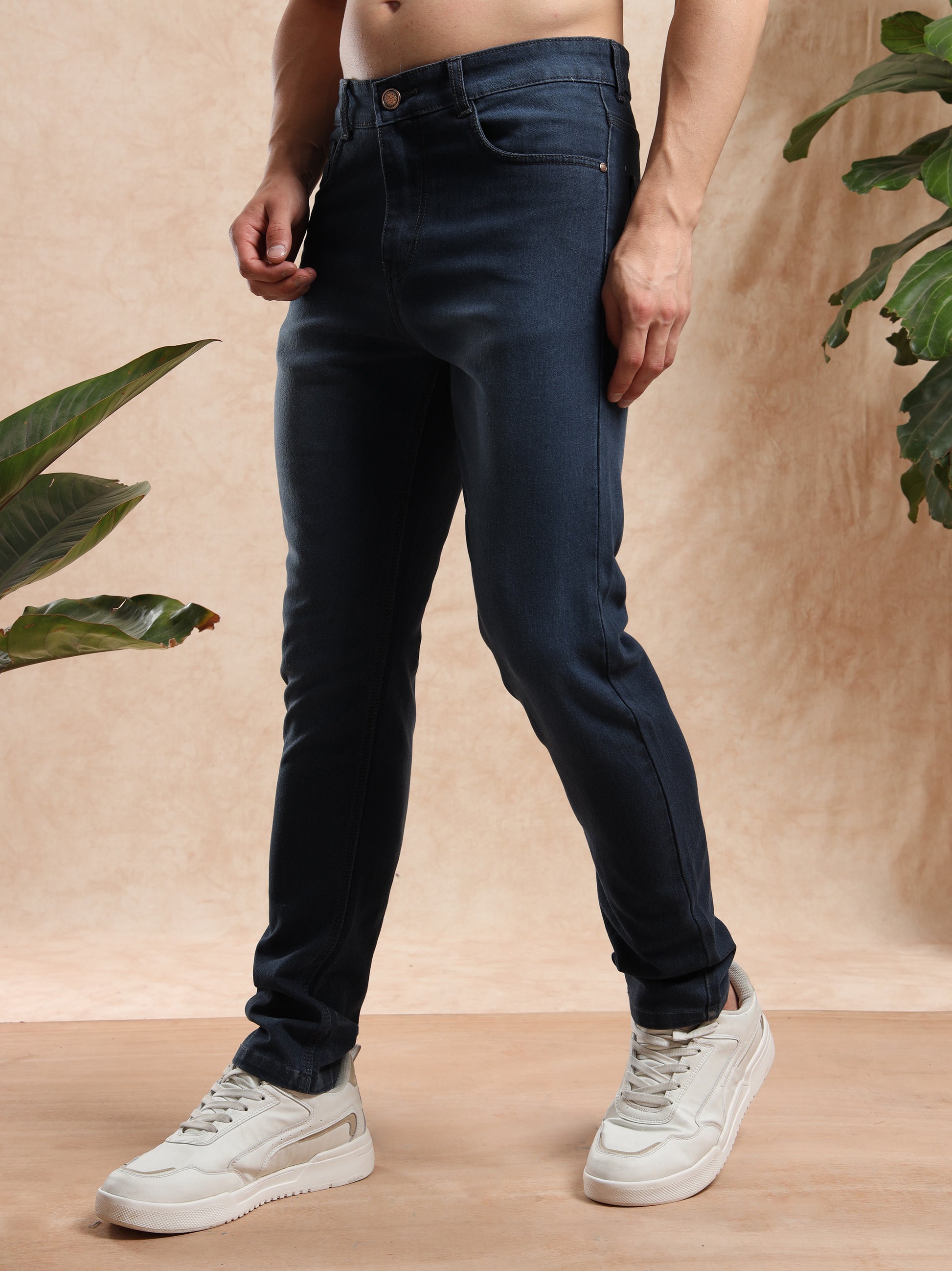 Stylish slim fit black denim jeans for men, side profile with casual sneakers.