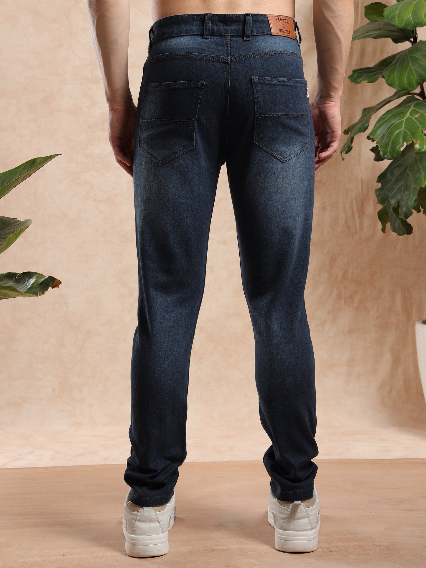 Men’s slim fit black washed jeans with back pockets and leather brand patch, rear view.