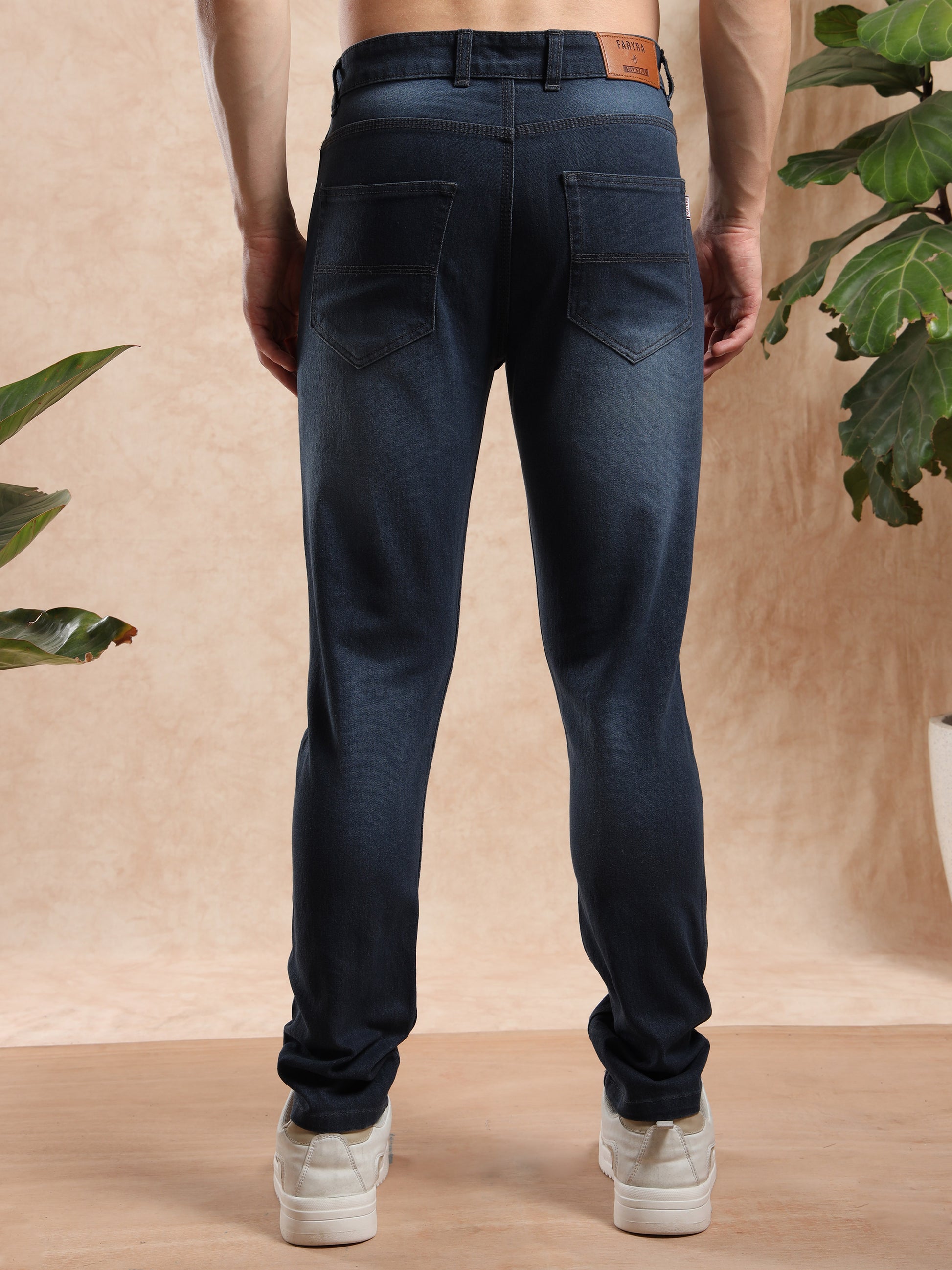 Men’s slim fit black washed jeans with back pockets and leather brand patch, rear view.