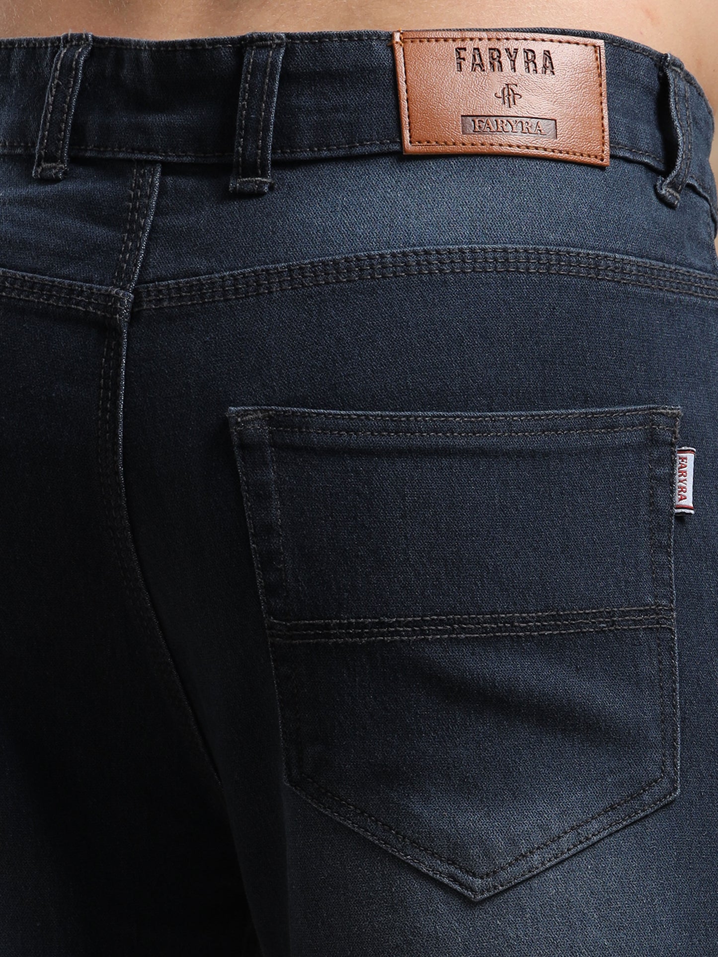 Back close-up of men’s denim jeans showing Faryra leather patch and stitched pockets