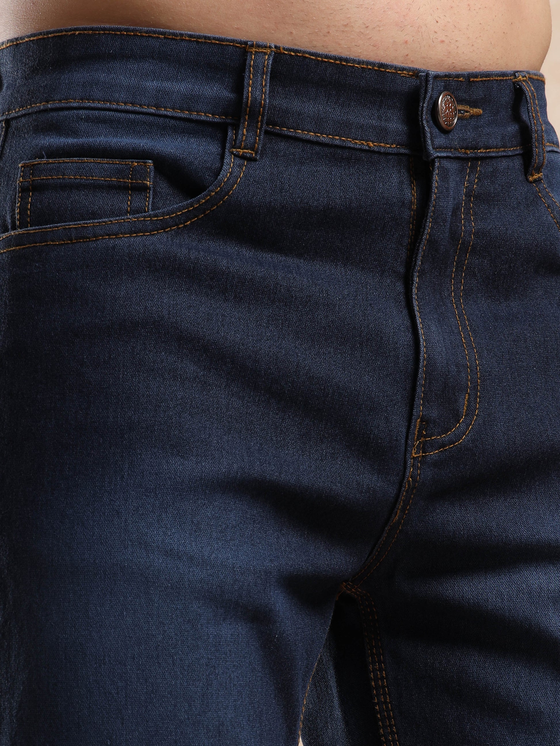 Detailed view of men’s slim fit dark blue jeans with coin pocket and button closure