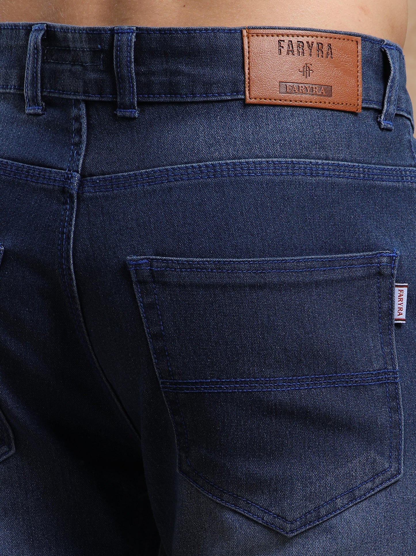 Back pocket with Faryra leather patch branding on slim fit mid blue denim jeans