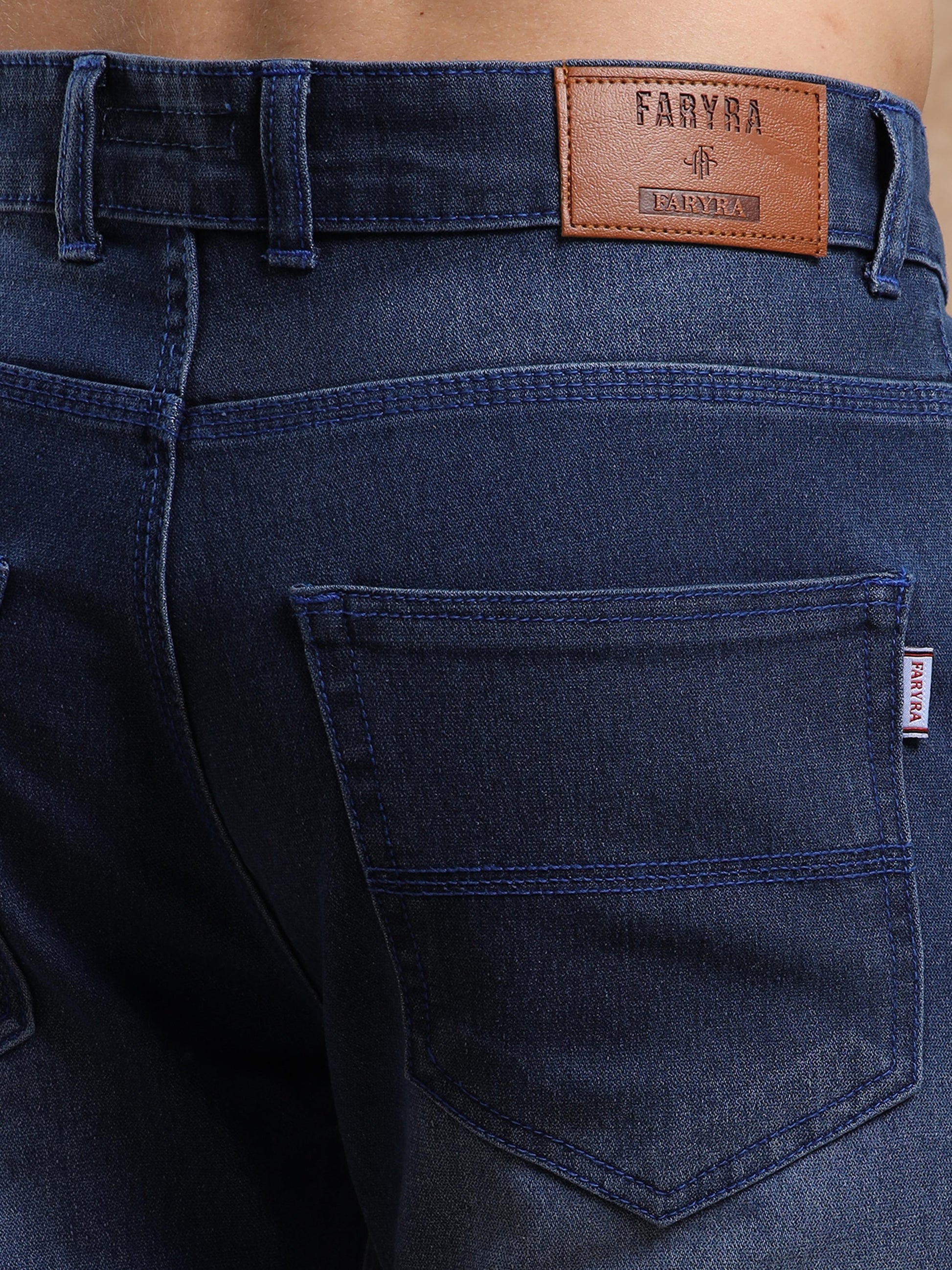 Back pocket with Faryra leather patch branding on slim fit mid blue denim jeans