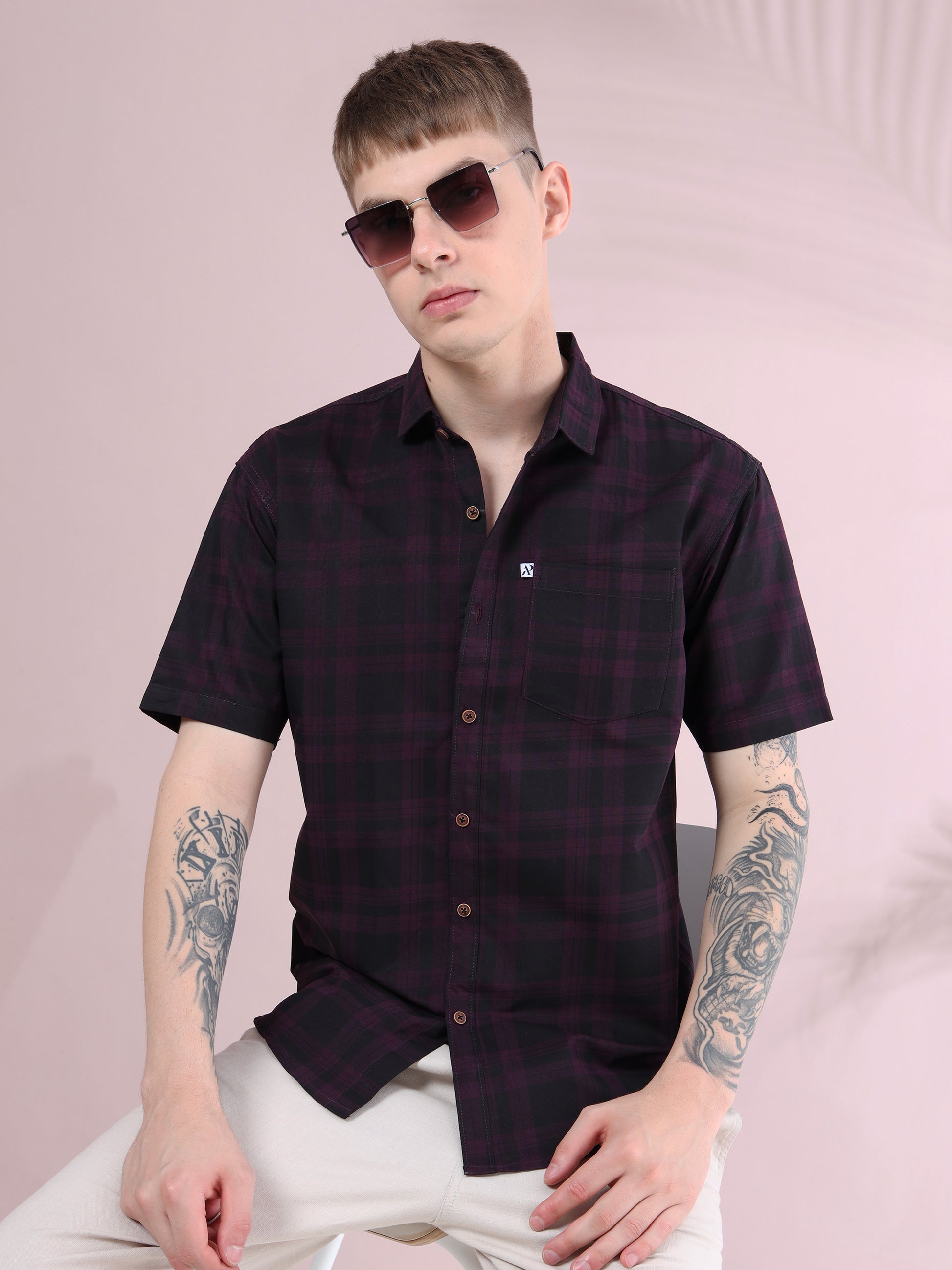 Men’s purple and black checked short sleeve cotton shirt styled with beige pants, accessorized with sunglasses.