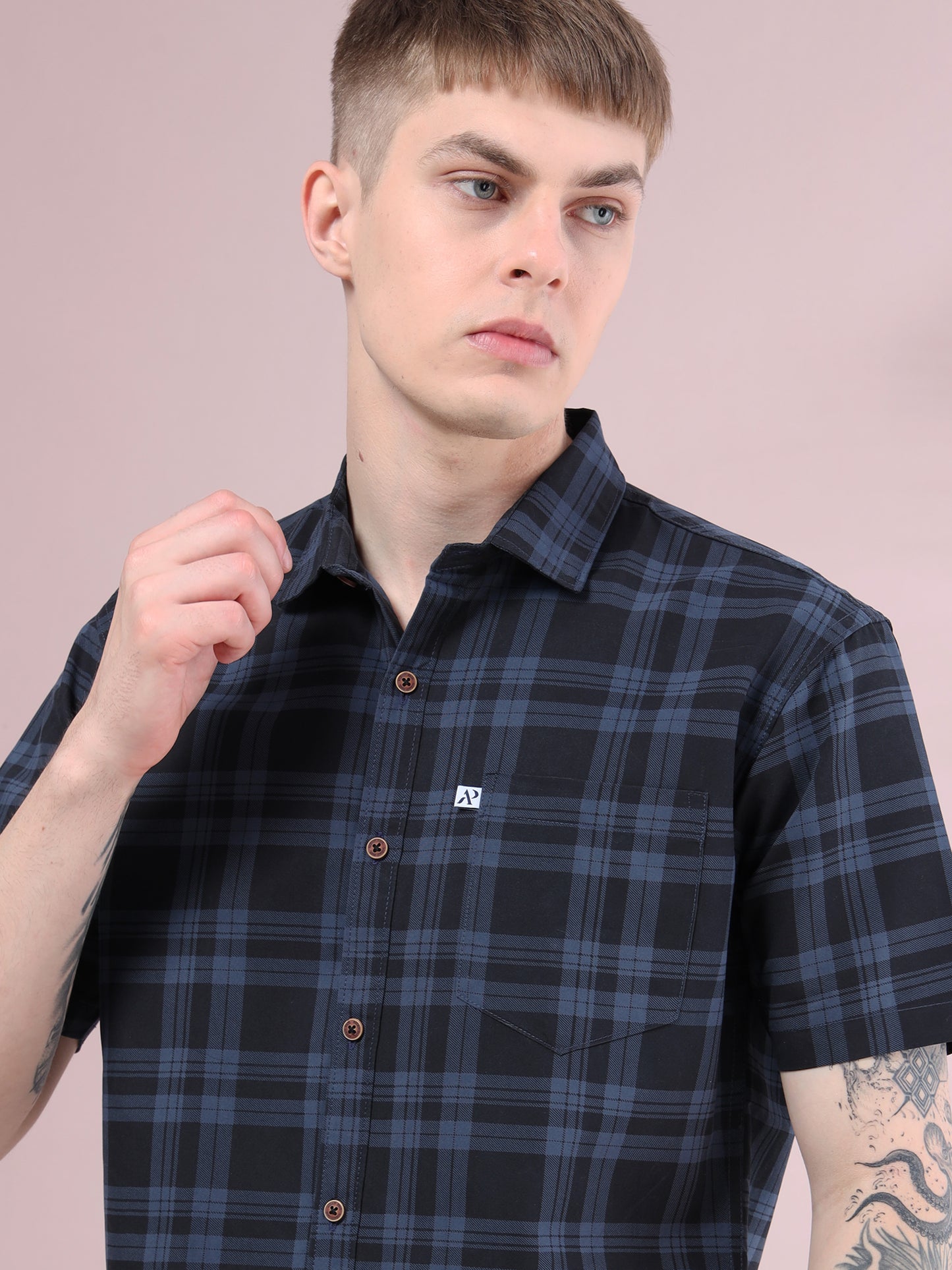 Close-up view of ash grey and black checked shirt with front pocket and brown button details.