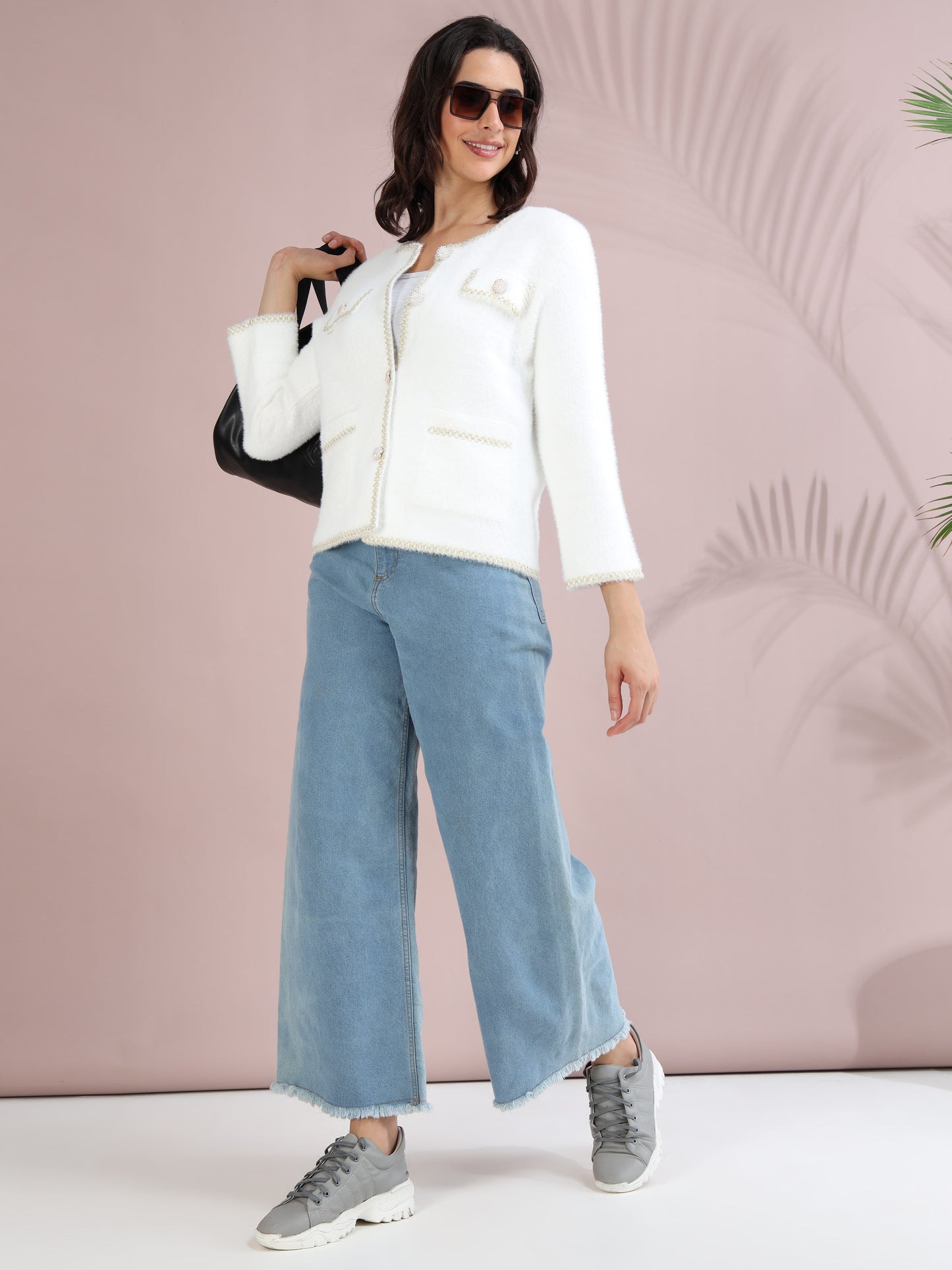 white pearl button cardigan with blue wide-leg jeans, sneakers, and sunglasses.
