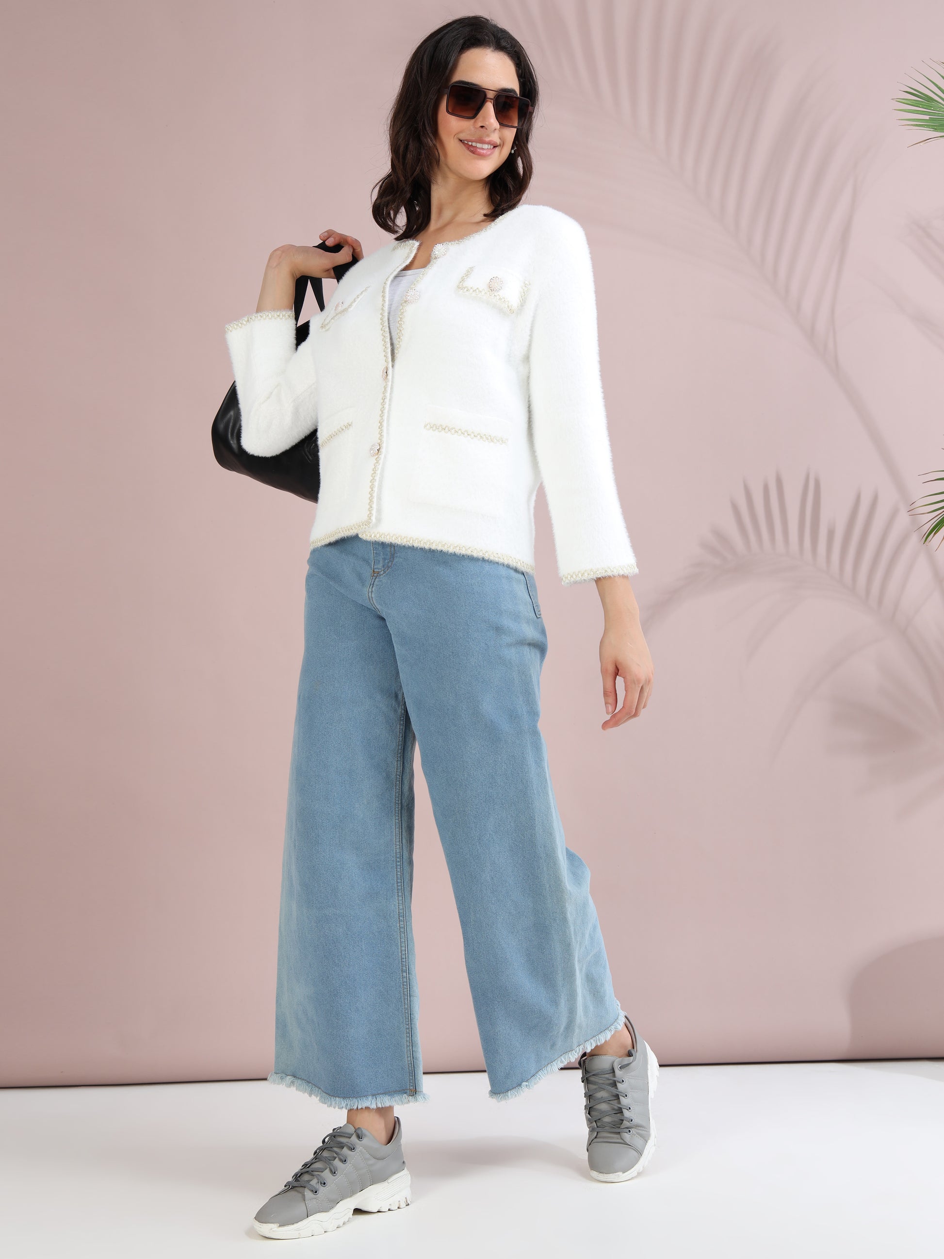 white pearl button cardigan with blue wide-leg jeans, sneakers, and sunglasses.