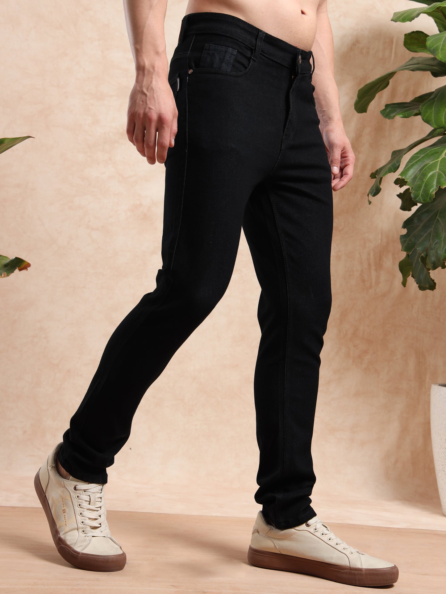 Angled side profile of black skinny fit jeans with classic pockets