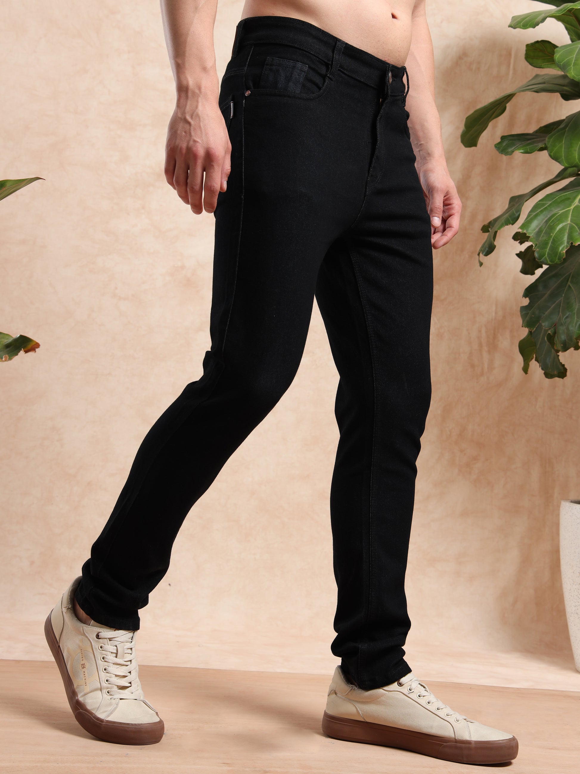 Angled side profile of black skinny fit jeans with classic pockets