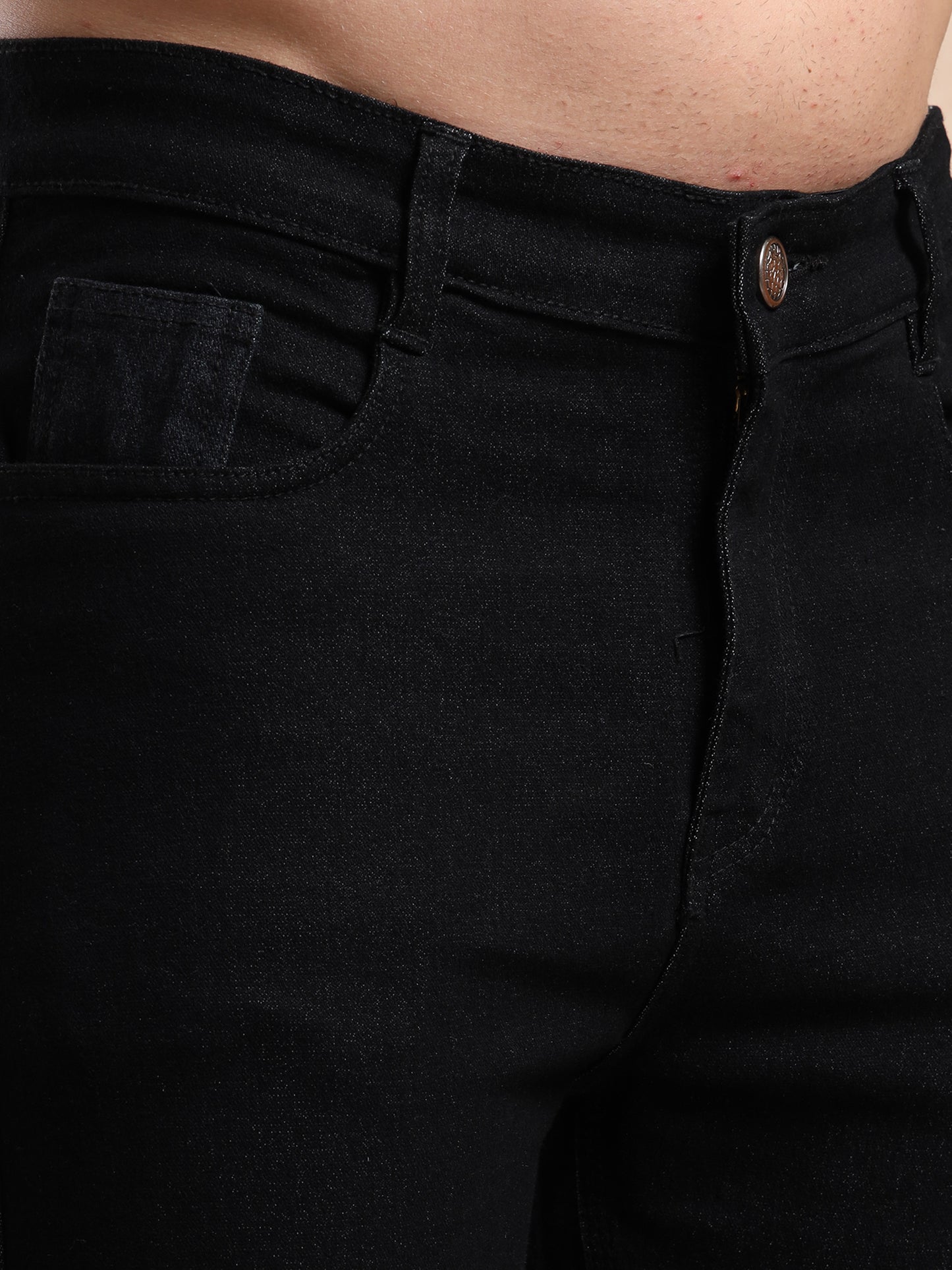 Close-up front pocket and button detail of black denim jeans