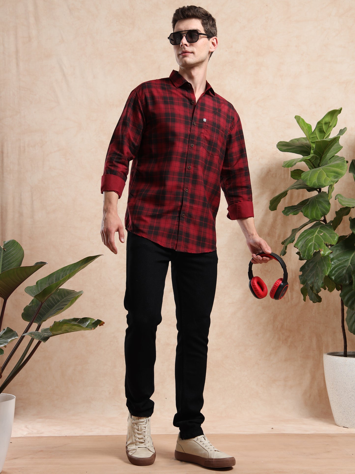 Men’s red and black checkered casual shirt with full sleeves, styled with sunglasses and headphones