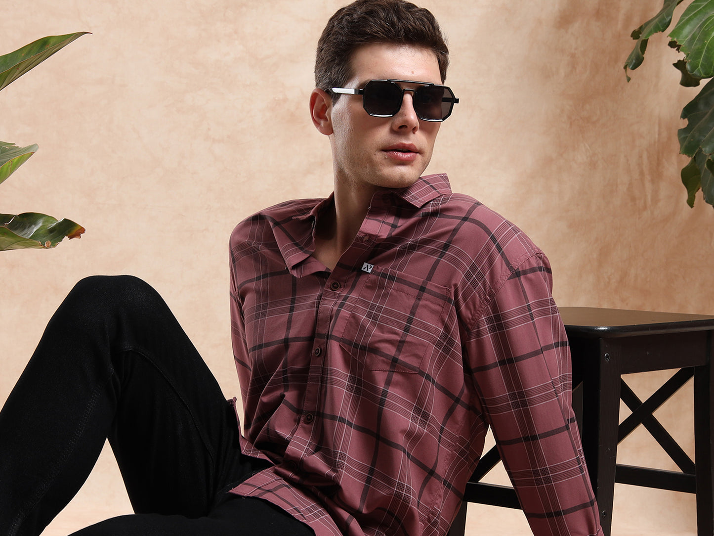 Model in maroon checkered shirt, black jeans, and sunglasses