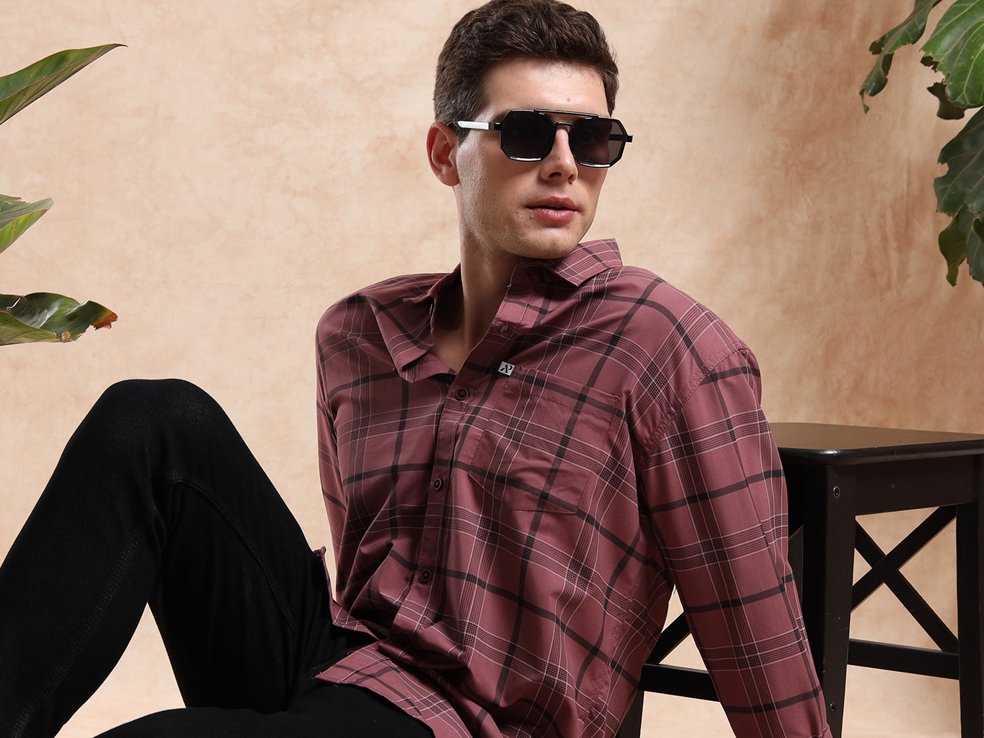 Model in maroon checkered shirt, black jeans, and sunglasses
