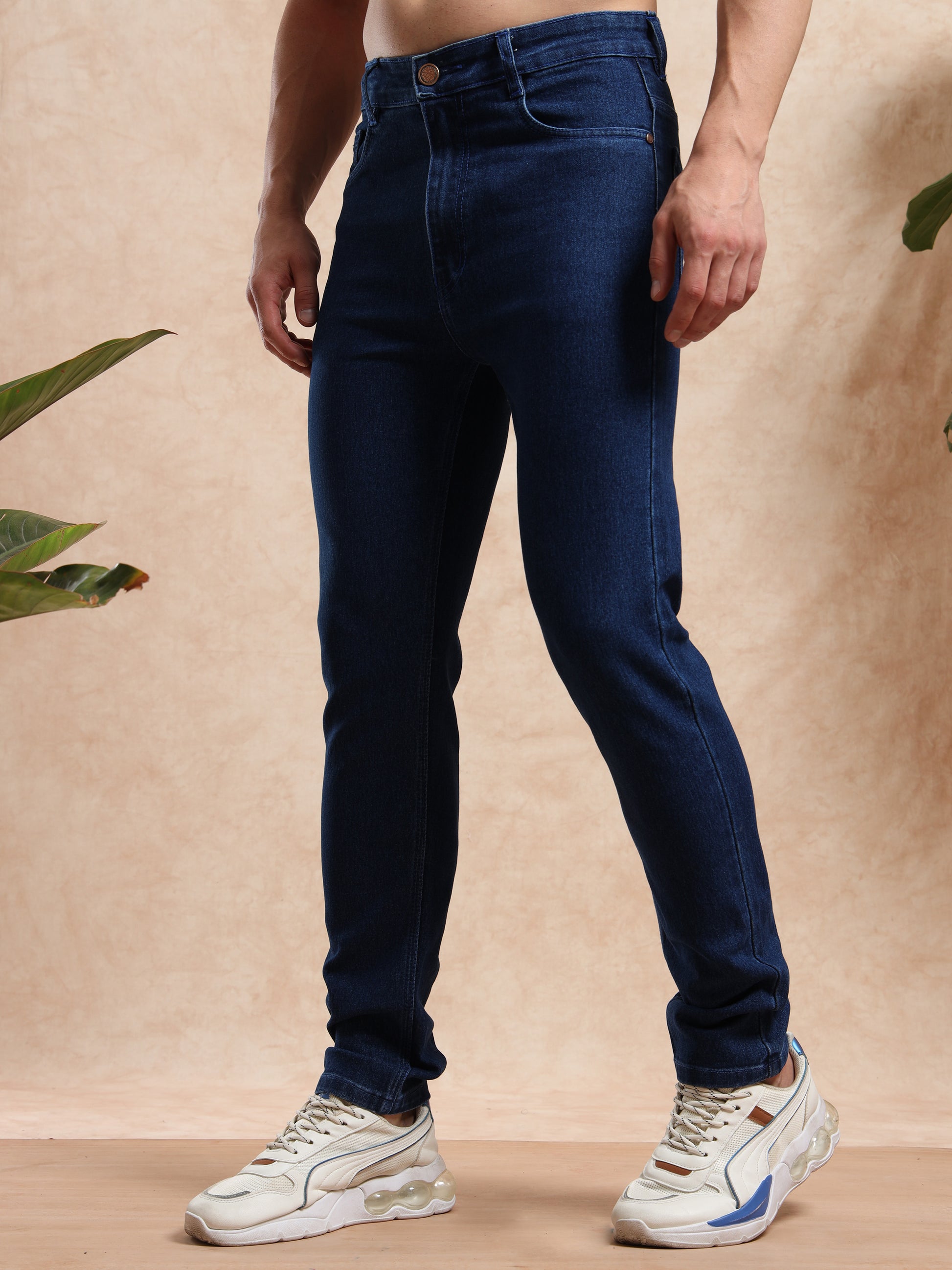 Men’s tapered slim fit jeans in dark blue denim paired with chunky sneakers