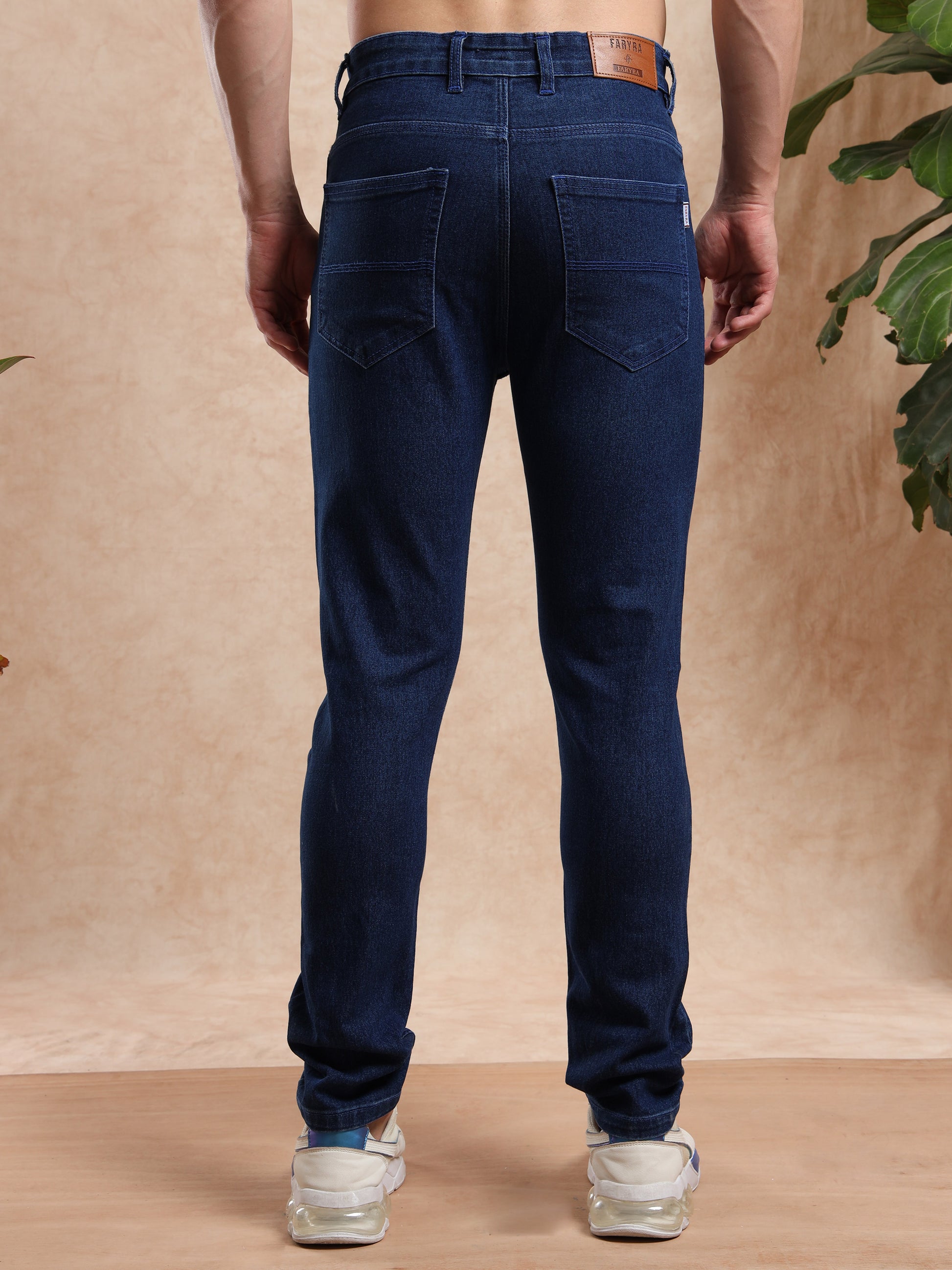 Back side of men’s slim fit dark blue jeans with patch pockets and leather brand tag