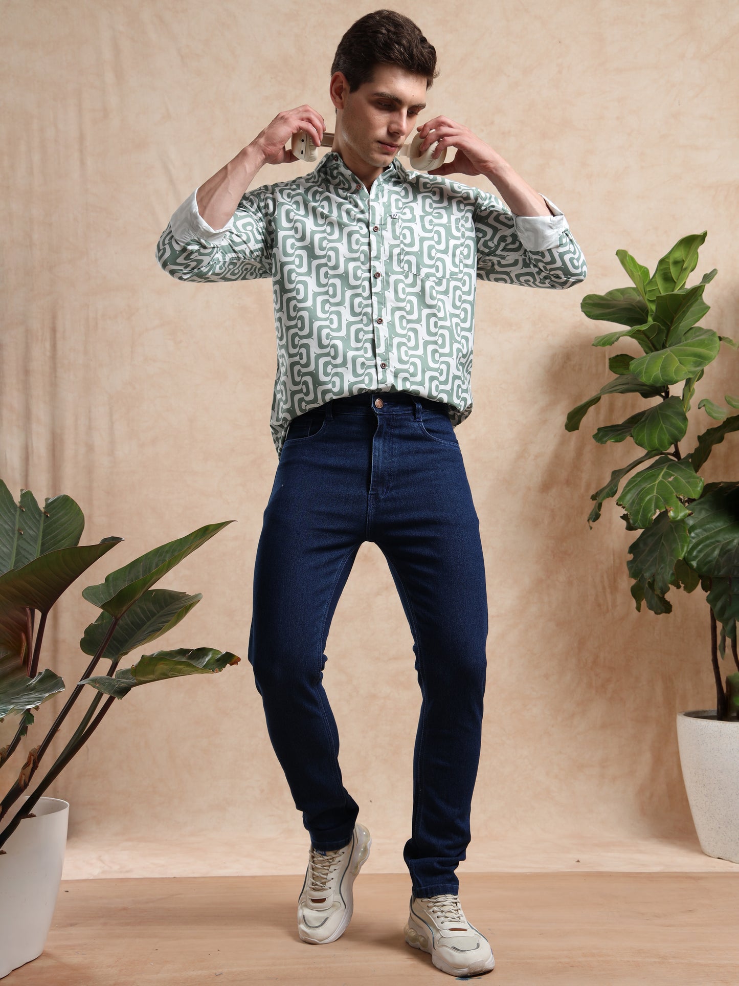 green printed shirt styled with dark jeans and white sneakers