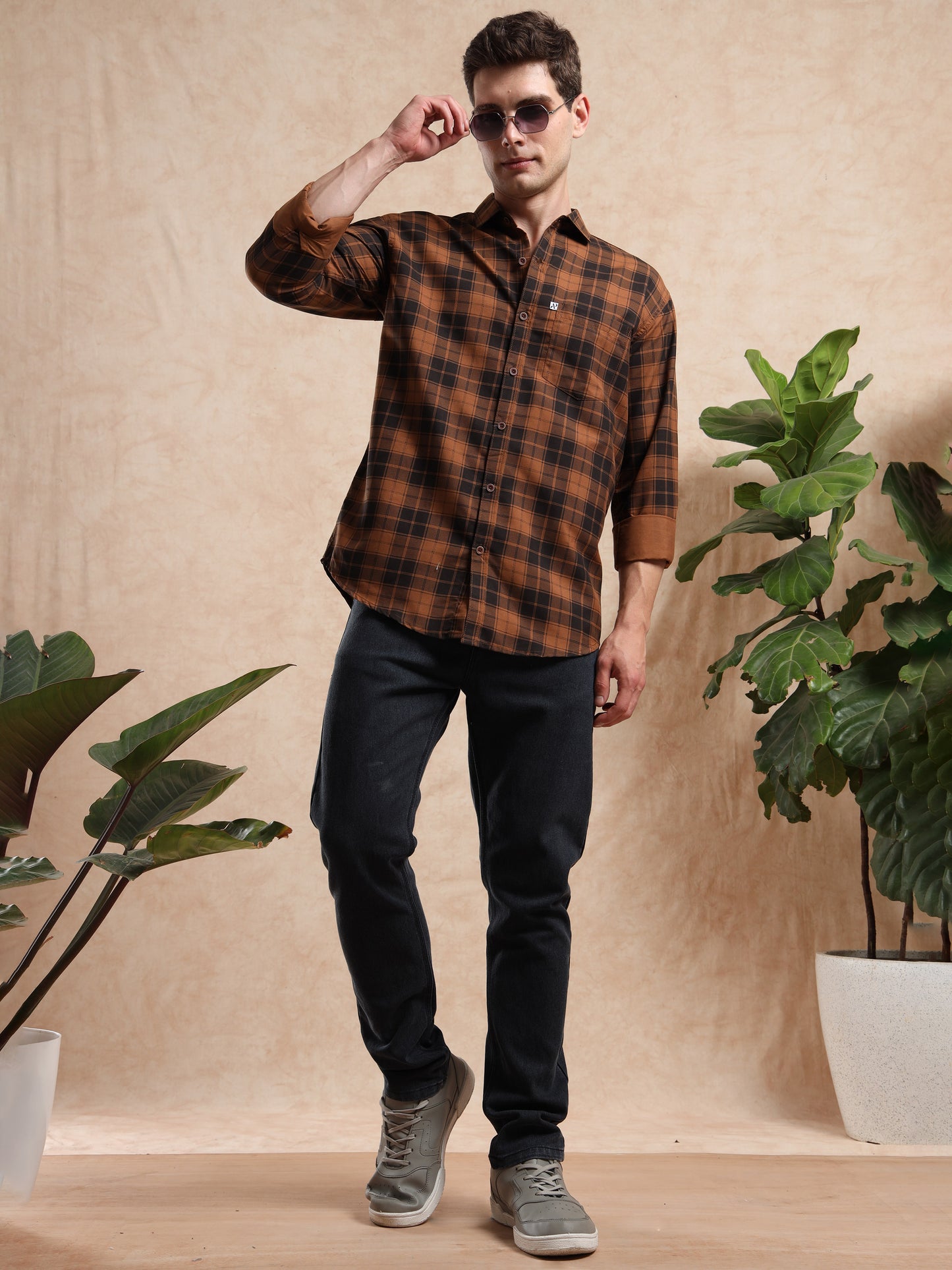 man in brown checked shirt paired with black jeans and sneakers