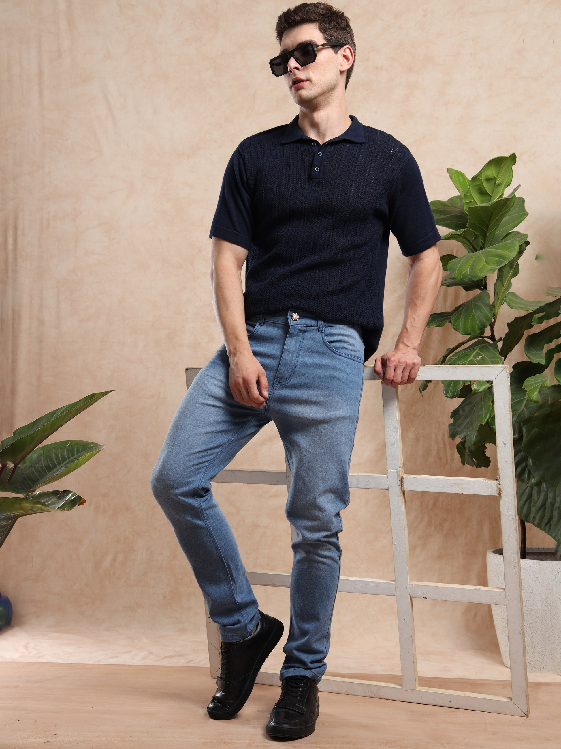 Model wearing slim fit blue jeans paired with black polo t-shirt and black sneakers.