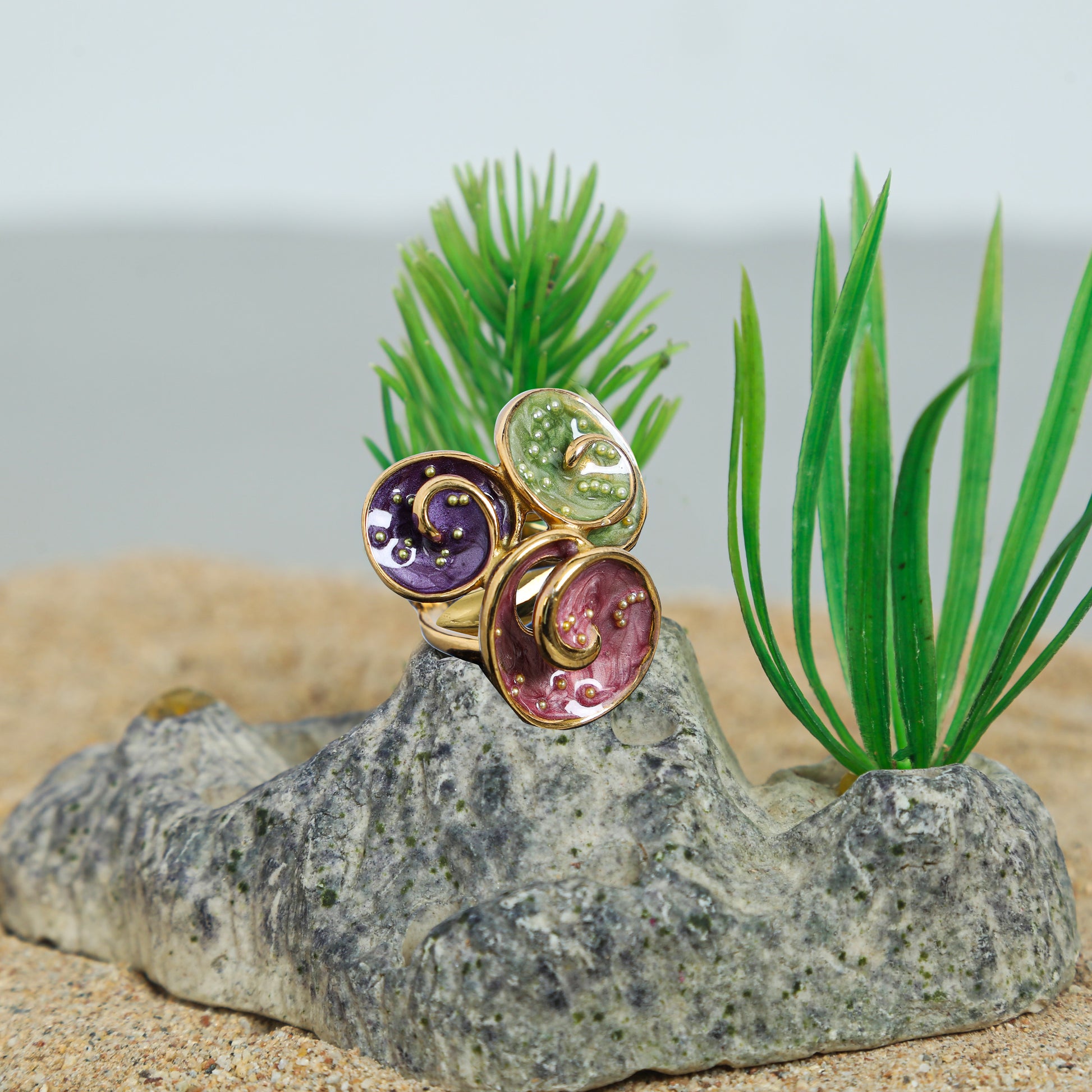 Gold-plated triple spiral statement ring with purple, green, and red enamel accents.