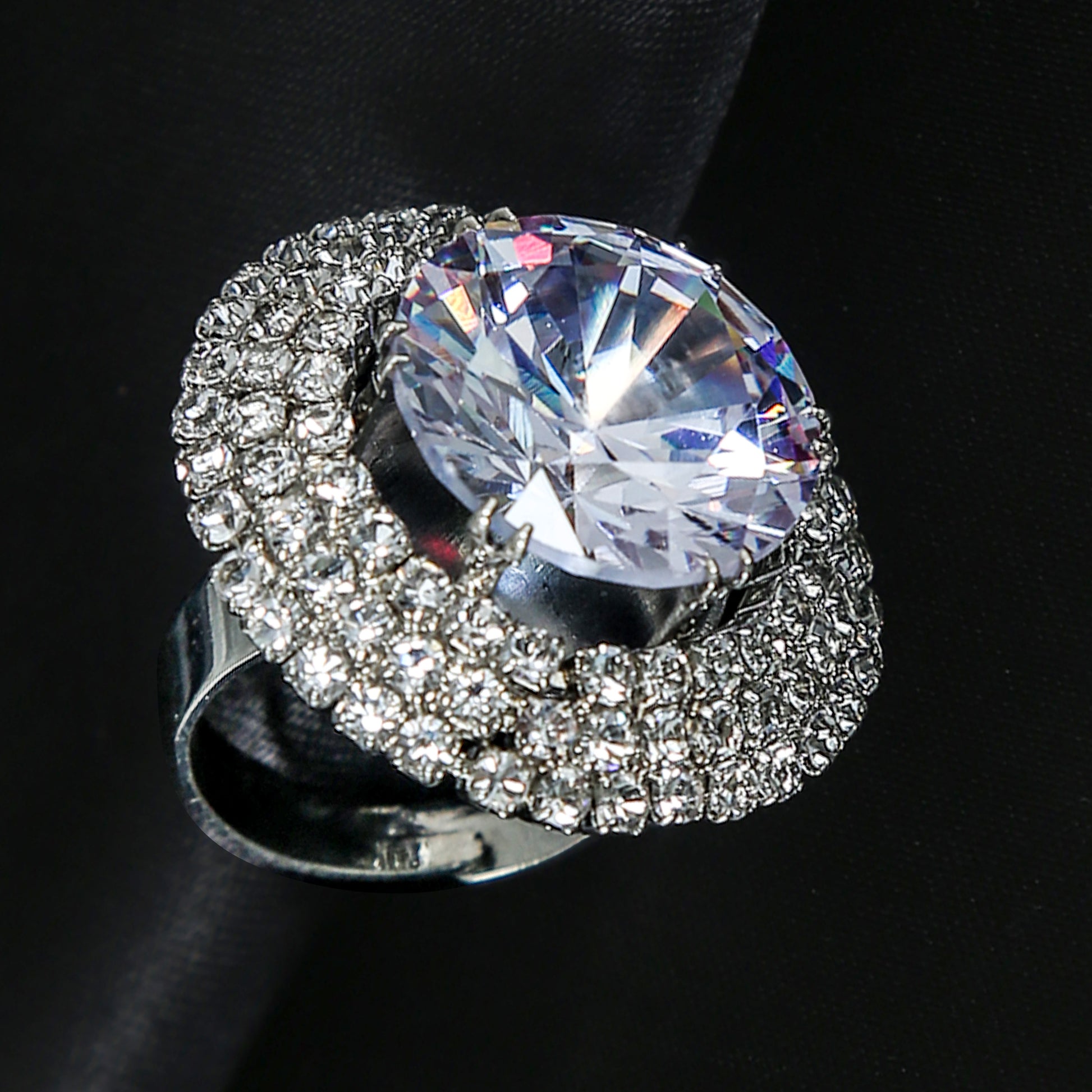 Close-up of a silver-plated zirconic stone ring with a large round-cut center stone surrounded by two rows of small sparkling crystals.