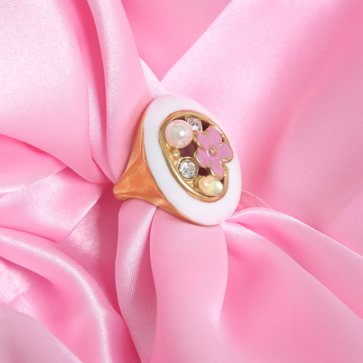 Gold-plated statement ring with white enamel base, pink floral design, pearl, and crystal accents