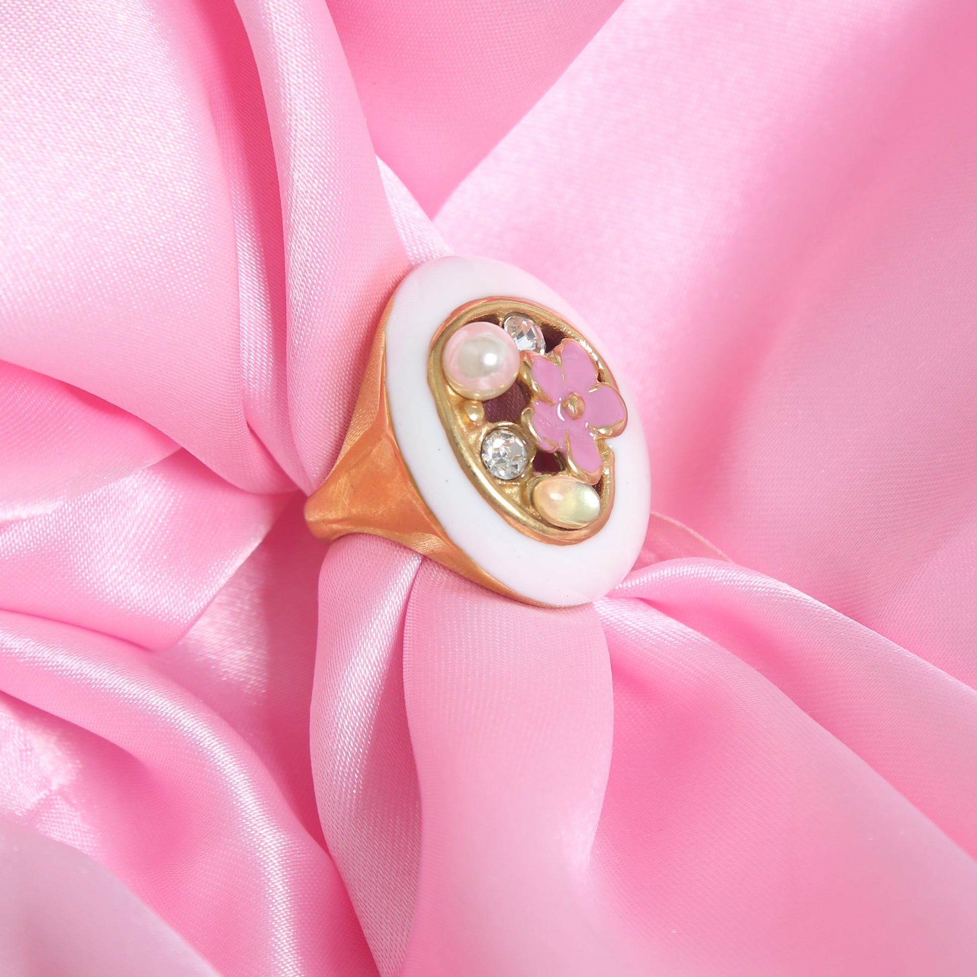 Gold-plated statement ring with white enamel base, pink floral design, pearl, and crystal accents
