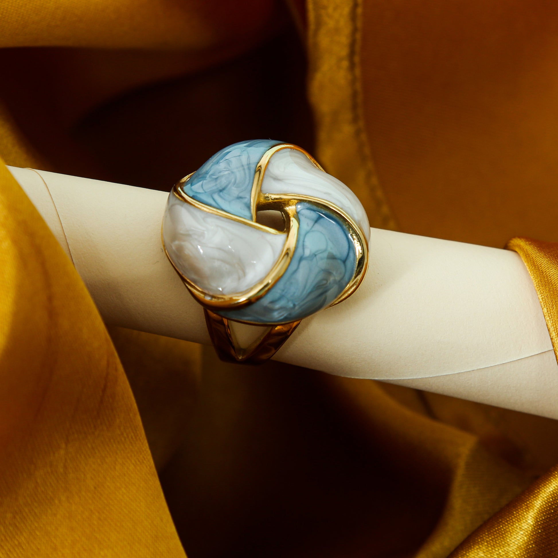Gold-plated statement ring with intertwined blue and white enamel design