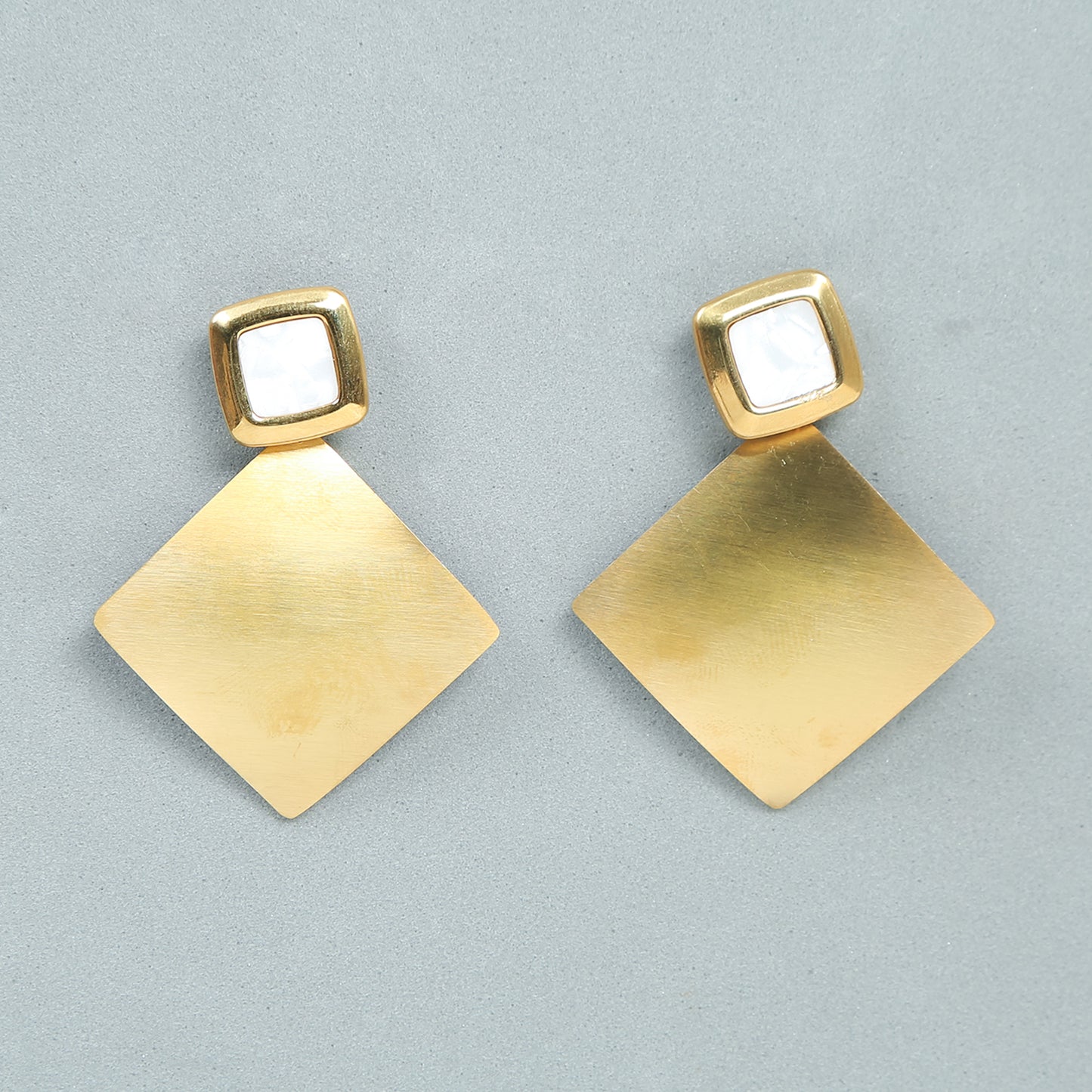 Gold geometric drop earrings with white stone studs and diamond-shaped dangle