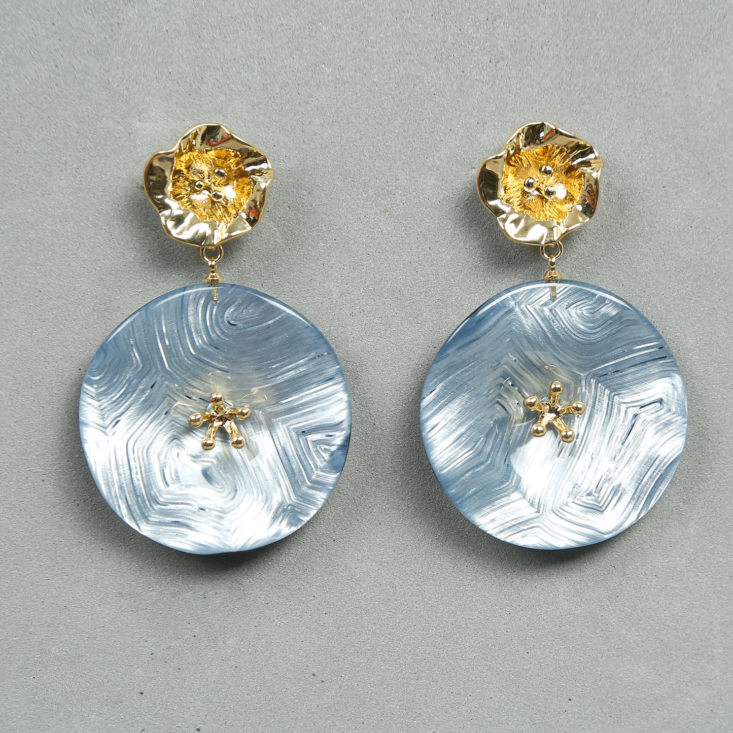 Gold floral stud earrings with large round blue marble resin drops featuring delicate golden accents