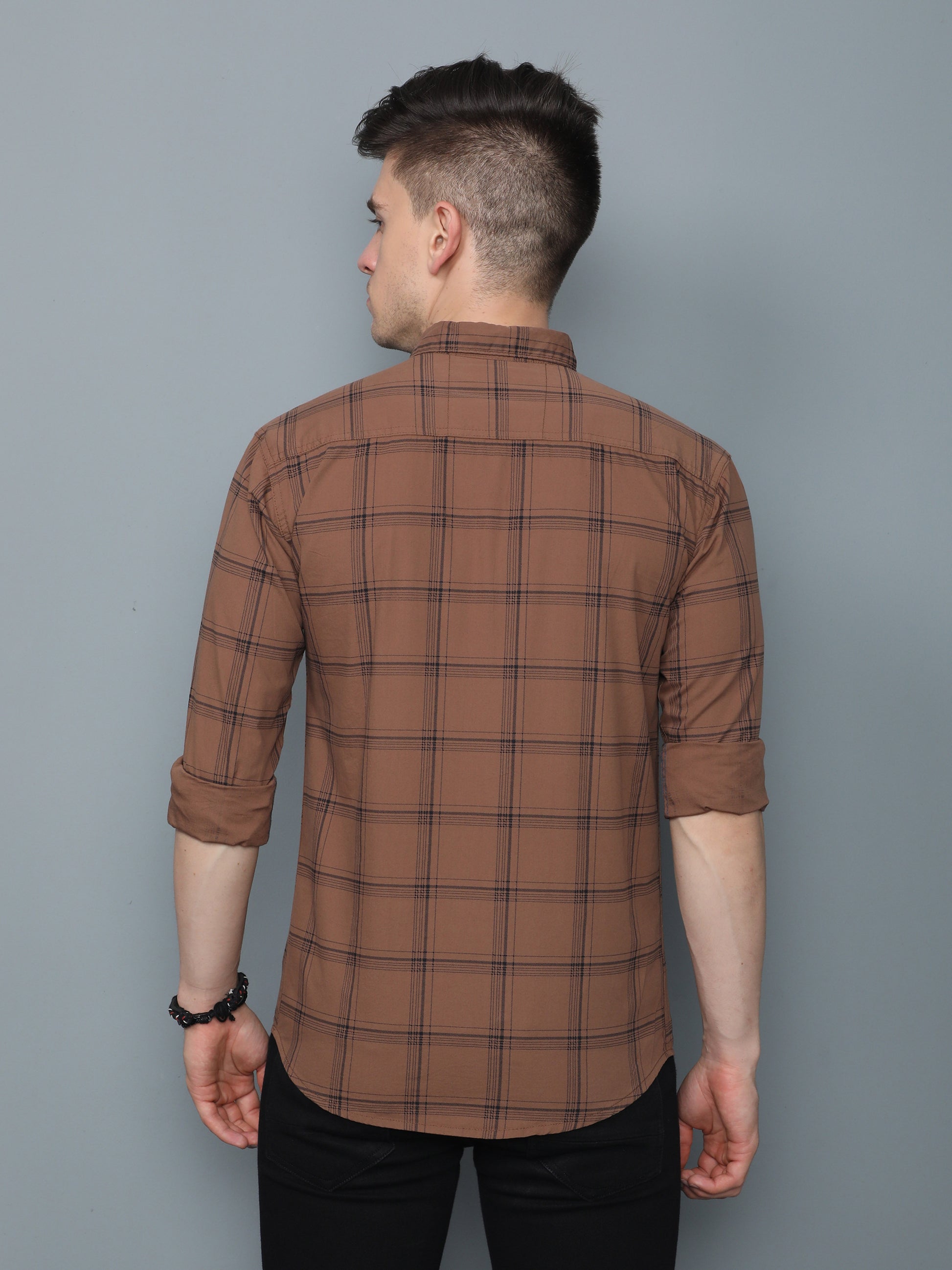 Back view of men’s brown check shirt with check pattern and rolled-up sleeves.