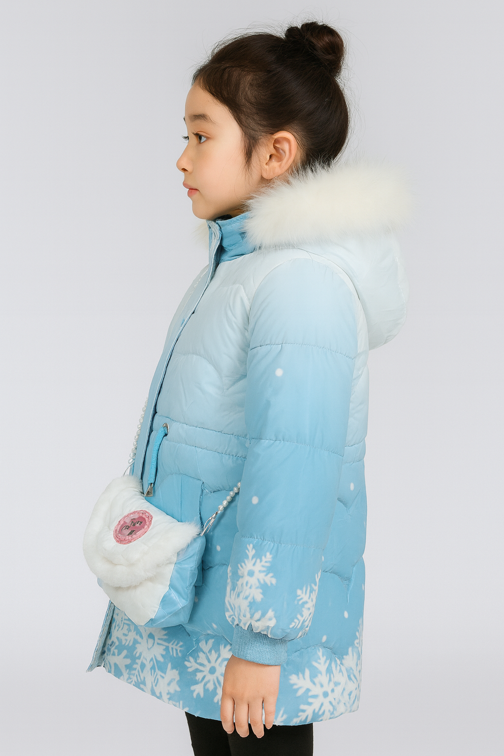 Side view of a light blue winter puffer jacket with white fur trim on the hood, decorated with white snowflake patterns and a small matching blue shoulder bag with a white faux fur flap and pearl strap.