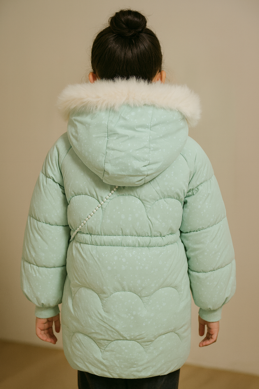 Back view of  a mint green padded winter coat with a fur-trimmed hood and subtle patterned texture