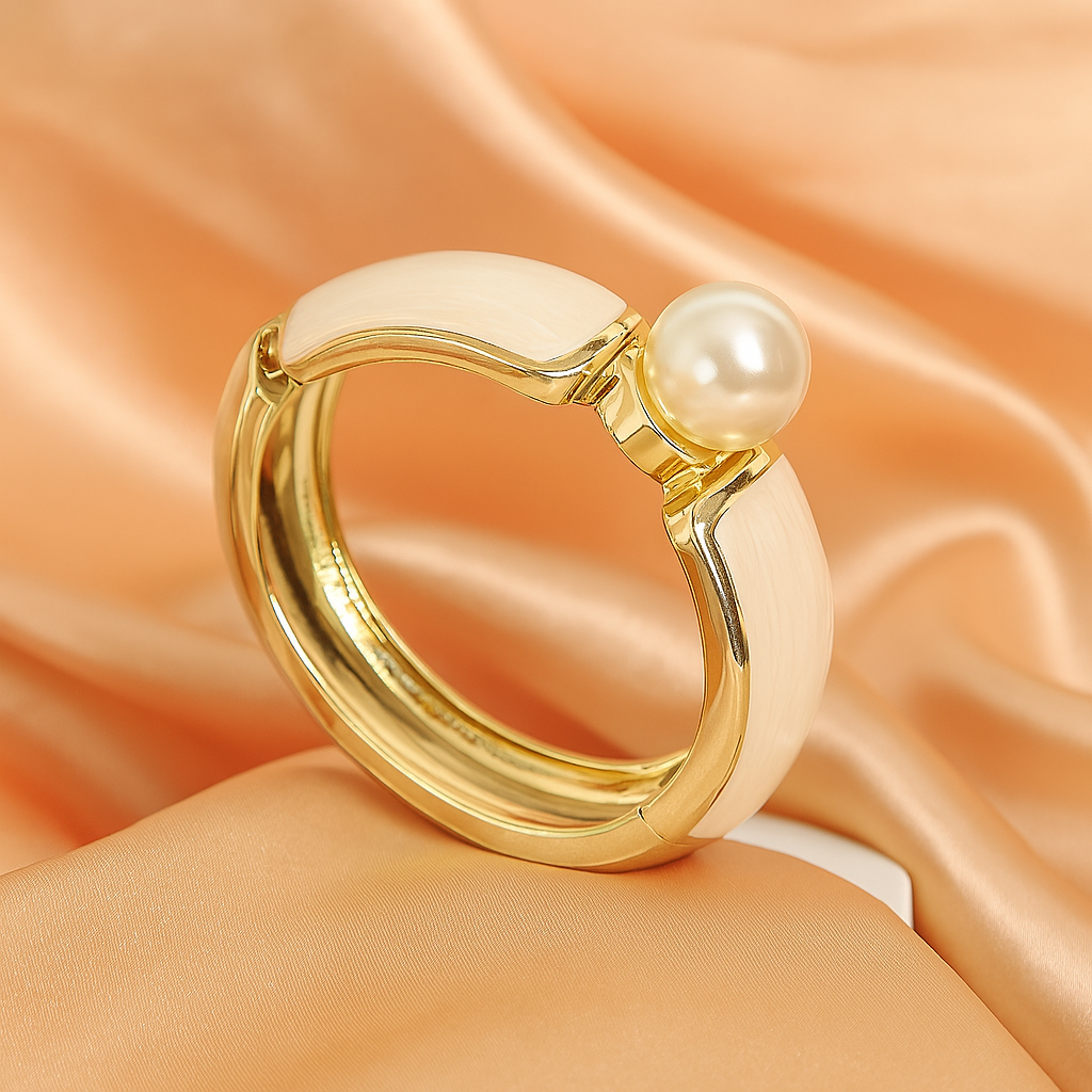 Stylish gold-plated bangle bracelet with cream enamel detailing and a prominent pearl