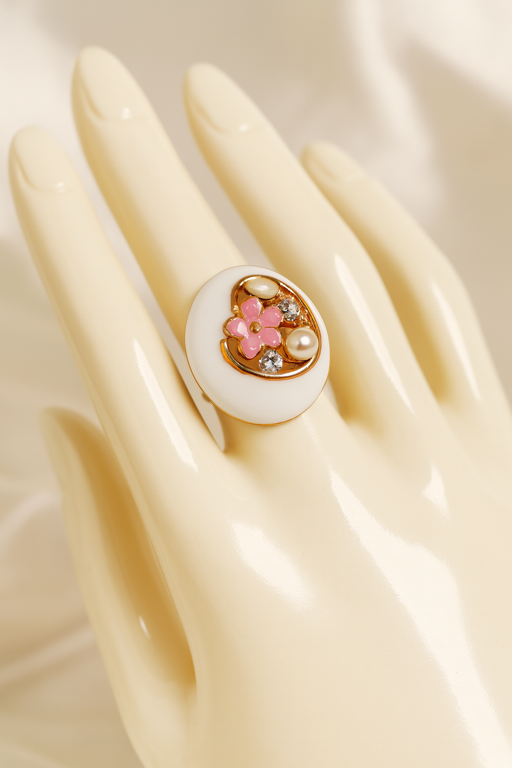 White enamel and gold-plated statement ring with pink floral centerpiece, pearls, and crystals