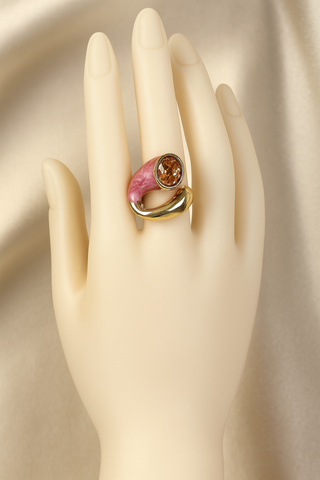 Stylish gold-plated ring with pink enamel and citrine gemstone showcased on a mannequin
