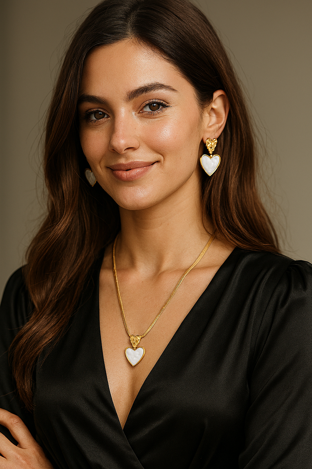 Woman wearing a gold heart pendant necklace and matching drop earrings with white stone center