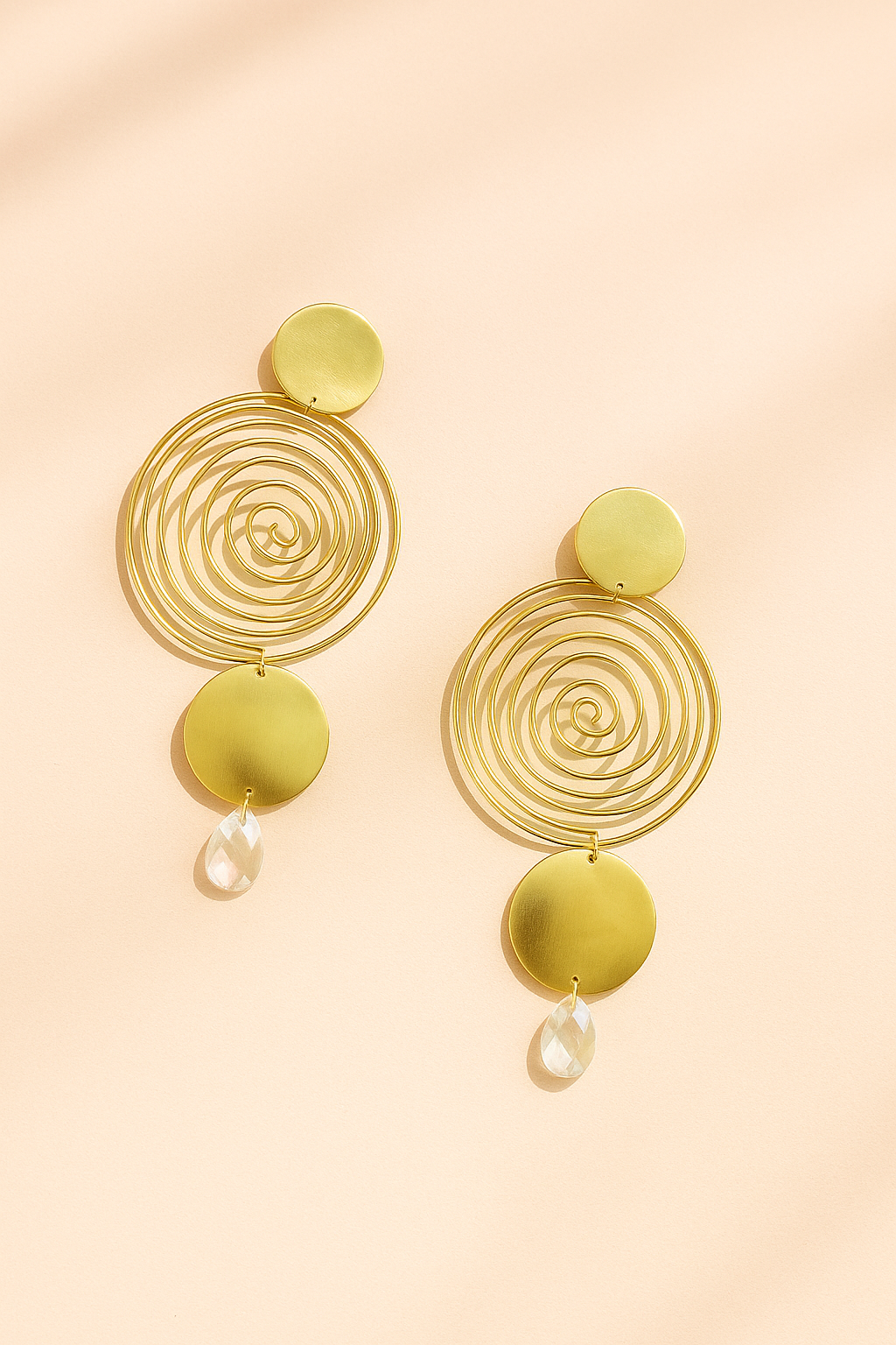 Pair of gold spiral statement earrings with circular discs and teardrop crystal