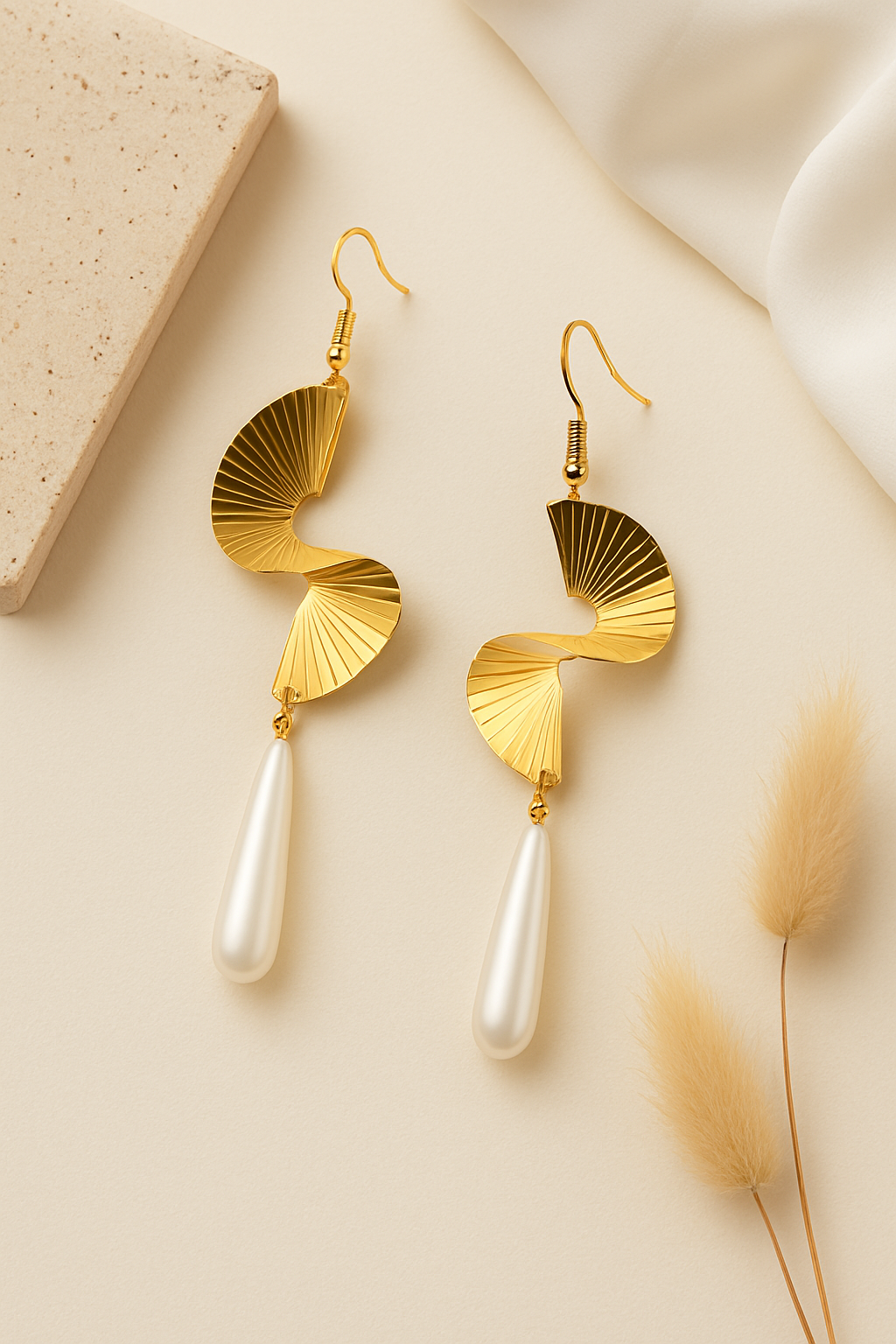Gold earrings with pearl drops on a beige background