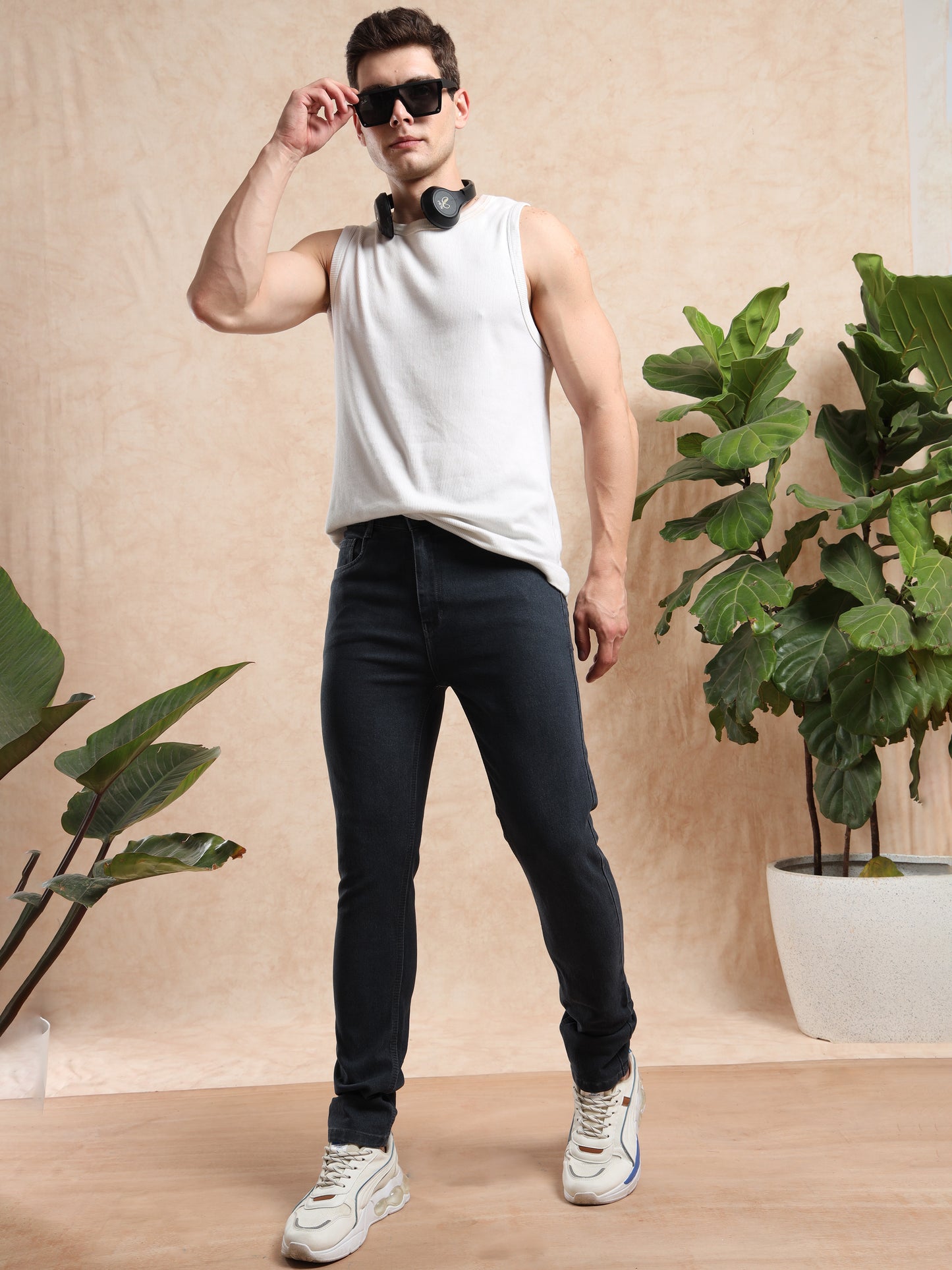 Men, slim fit grey jeans paired with sleeveless white t-shirt, sneakers, and sunglasses, casual street style fashion