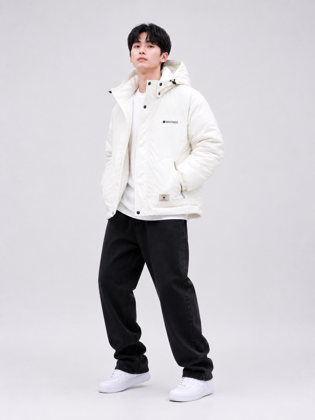 a white hooded puffer jacket with insulated padding, black relaxed-fit jeans, and white sneakers, styled for casual winter and streetwear fashion.