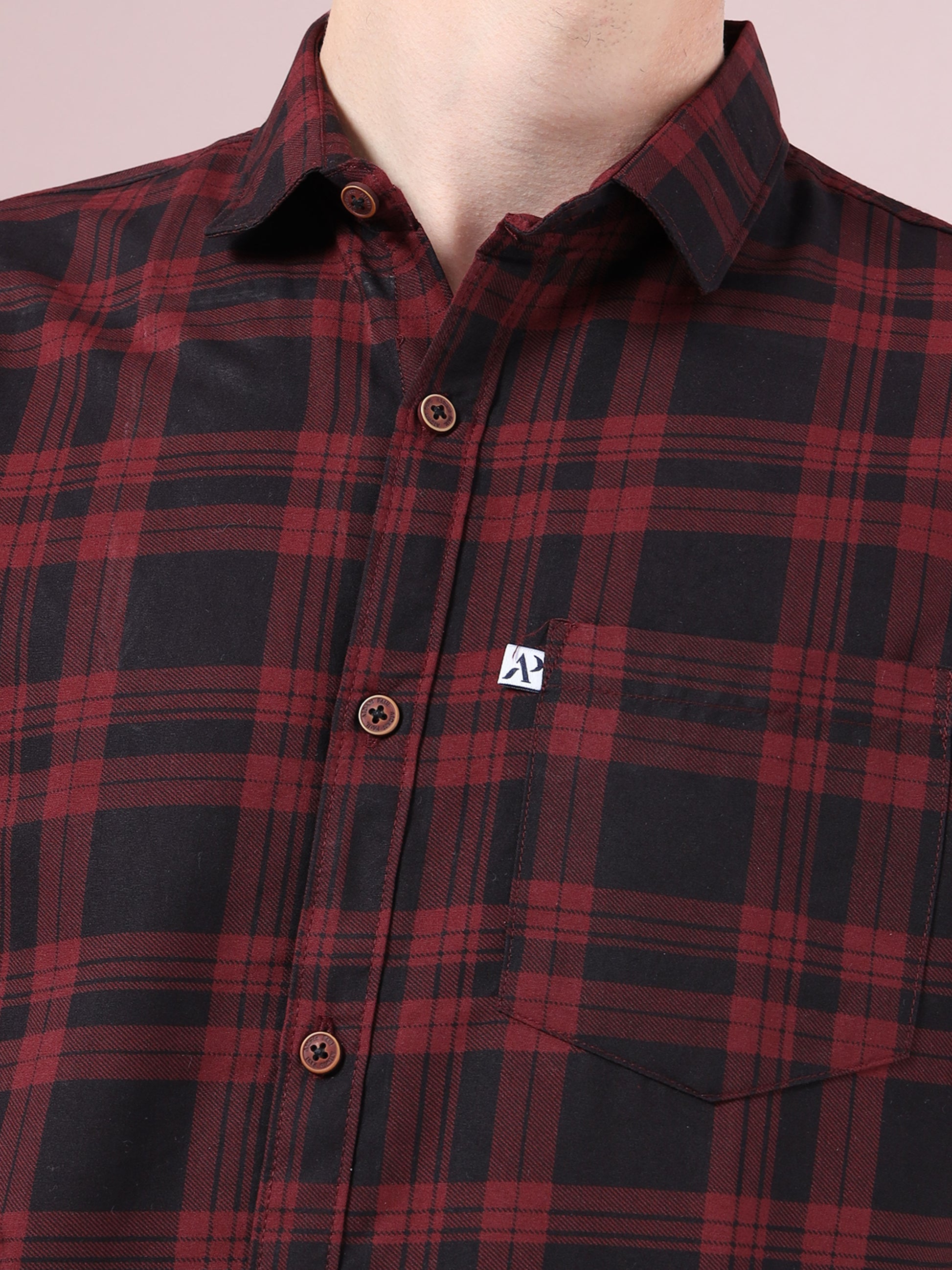 Close-up of maroon and black checkered shirt with button details and chest pocket.