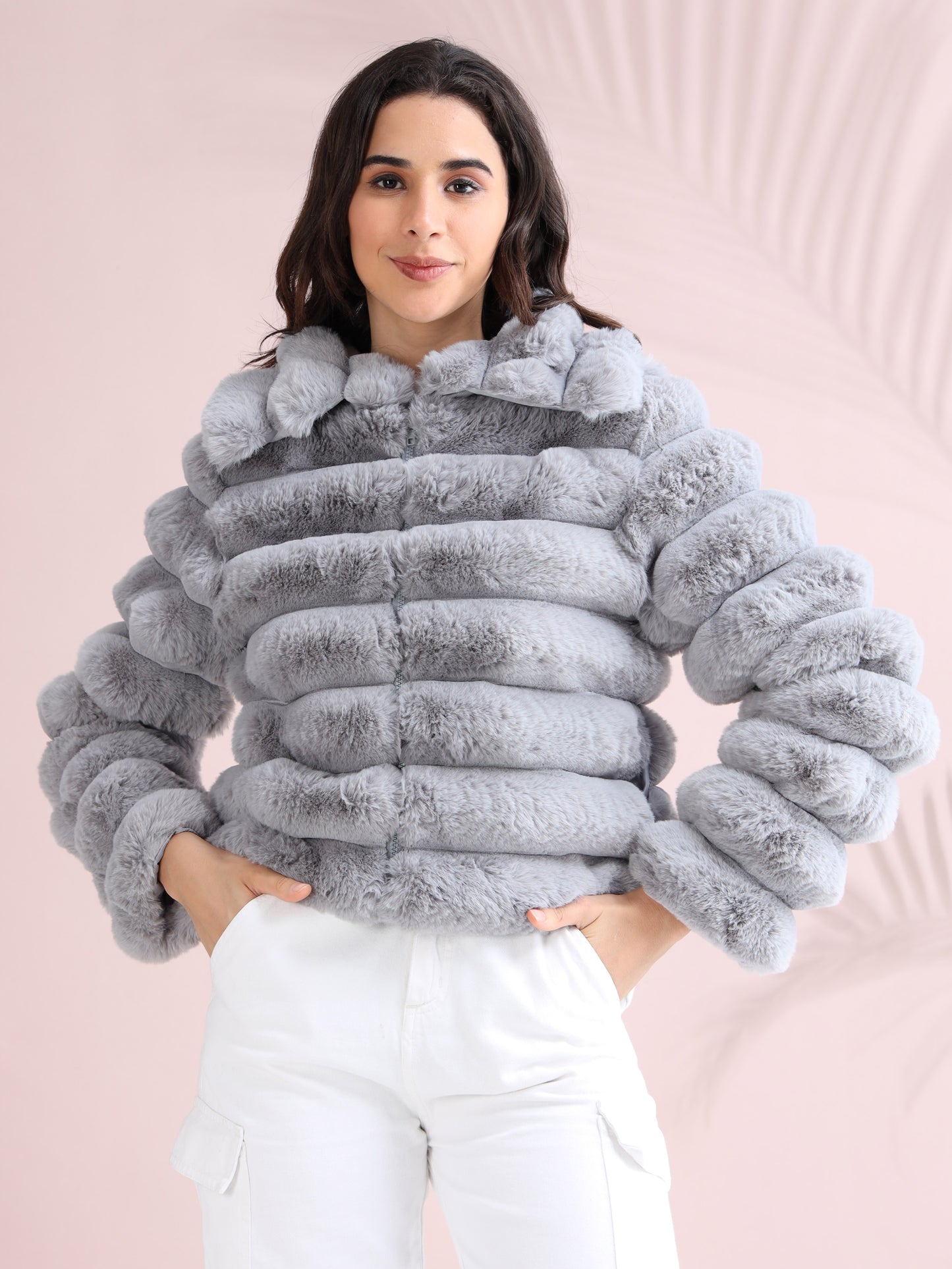 Woman wearing a stylish light grey faux fur puffer jacket with horizontal padded design, paired with white cargo pants.